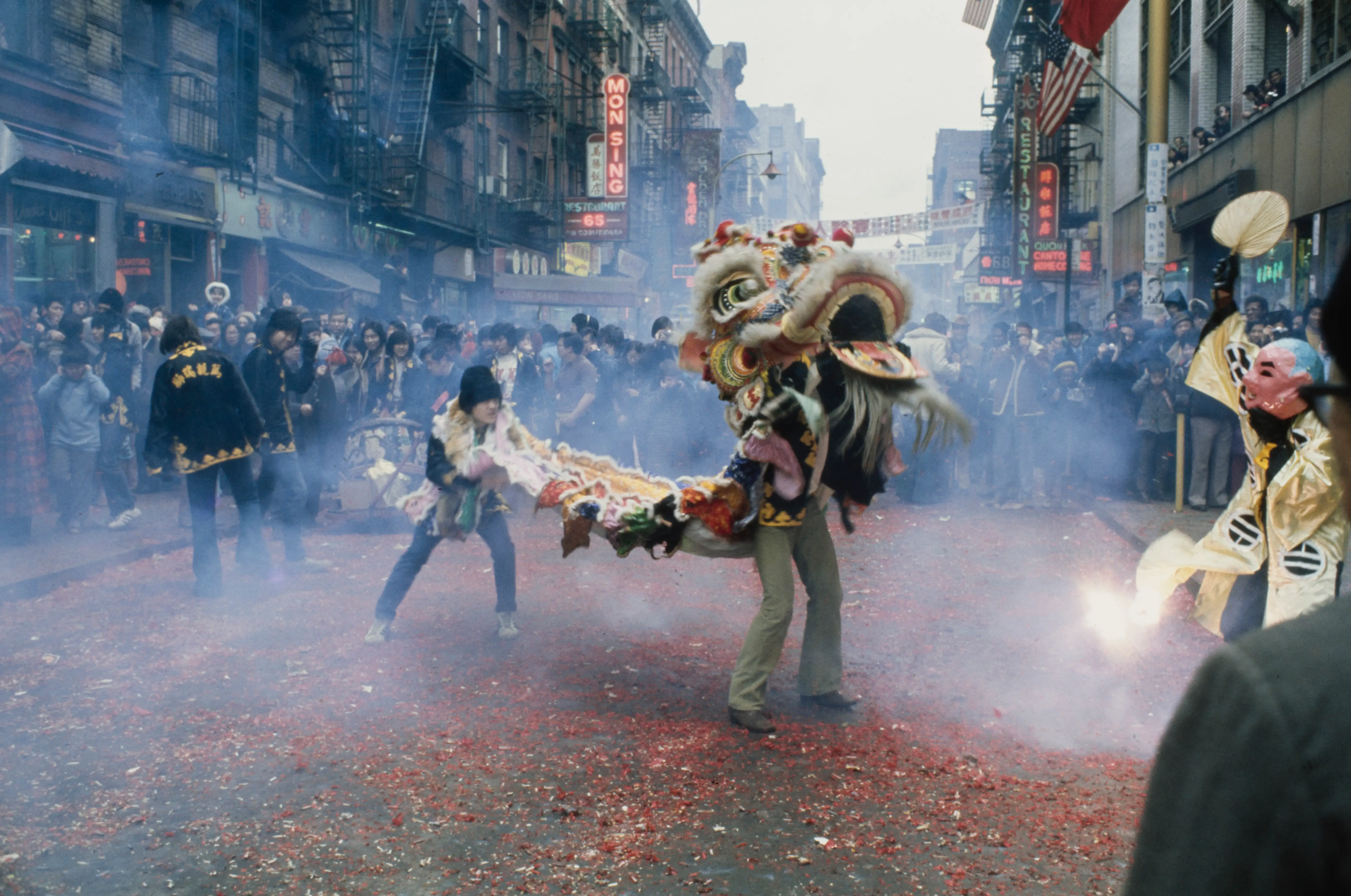 Chinese dancers throw firecrackers into the path of the Lion as they usher in the Year of the Ox with a drum-and-dragon ceremony, along Mott Street in the Chinatown neighbourhood of New York City, New York, 3rd February 1973. The Lion, owned by the various societies, is shown as it visits society members establishments.