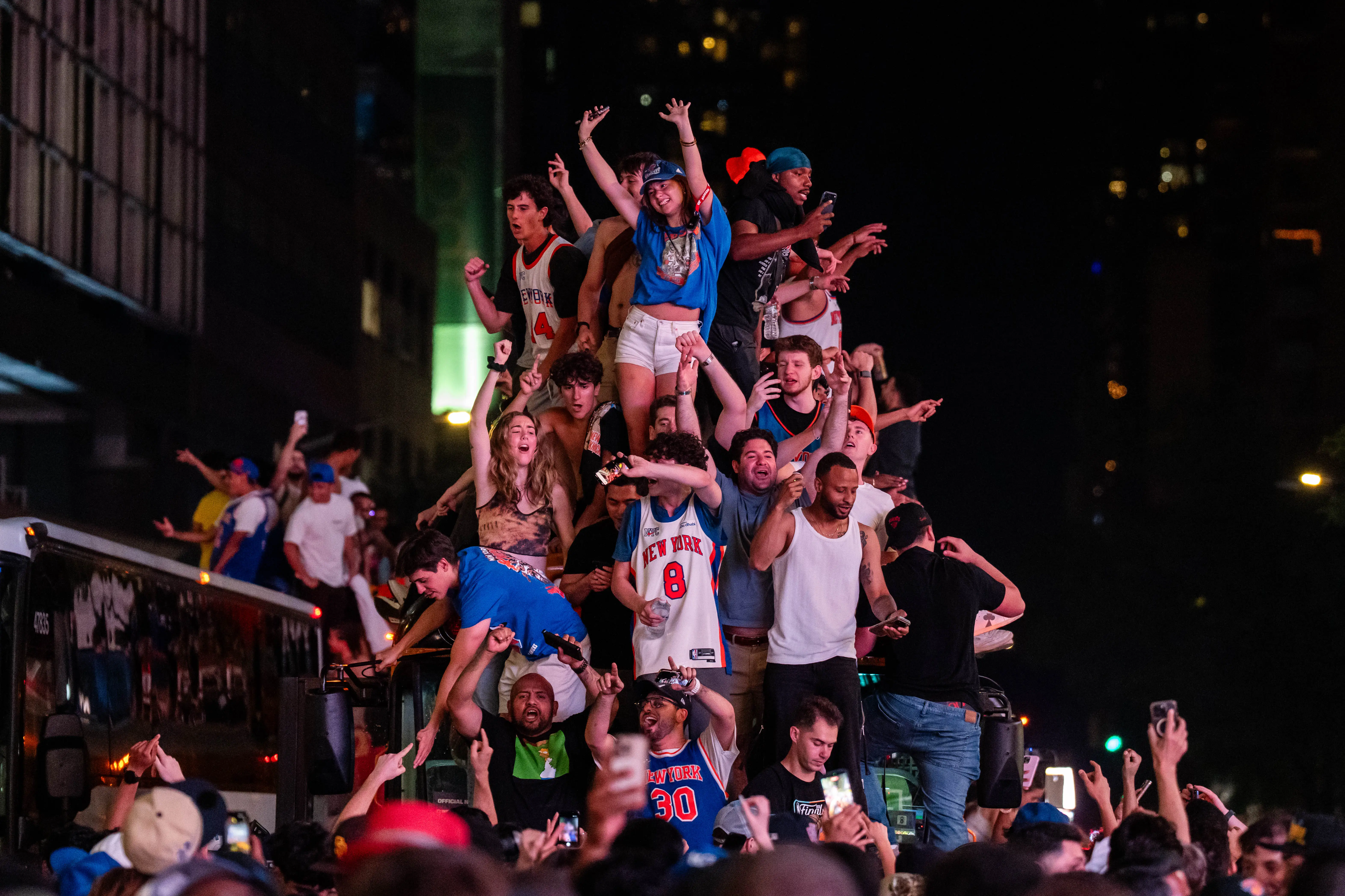 New York Knicks fans climb on buses as they celebrate after they win the NBA Finals in Times Square on June 14, 2026 in New York City.