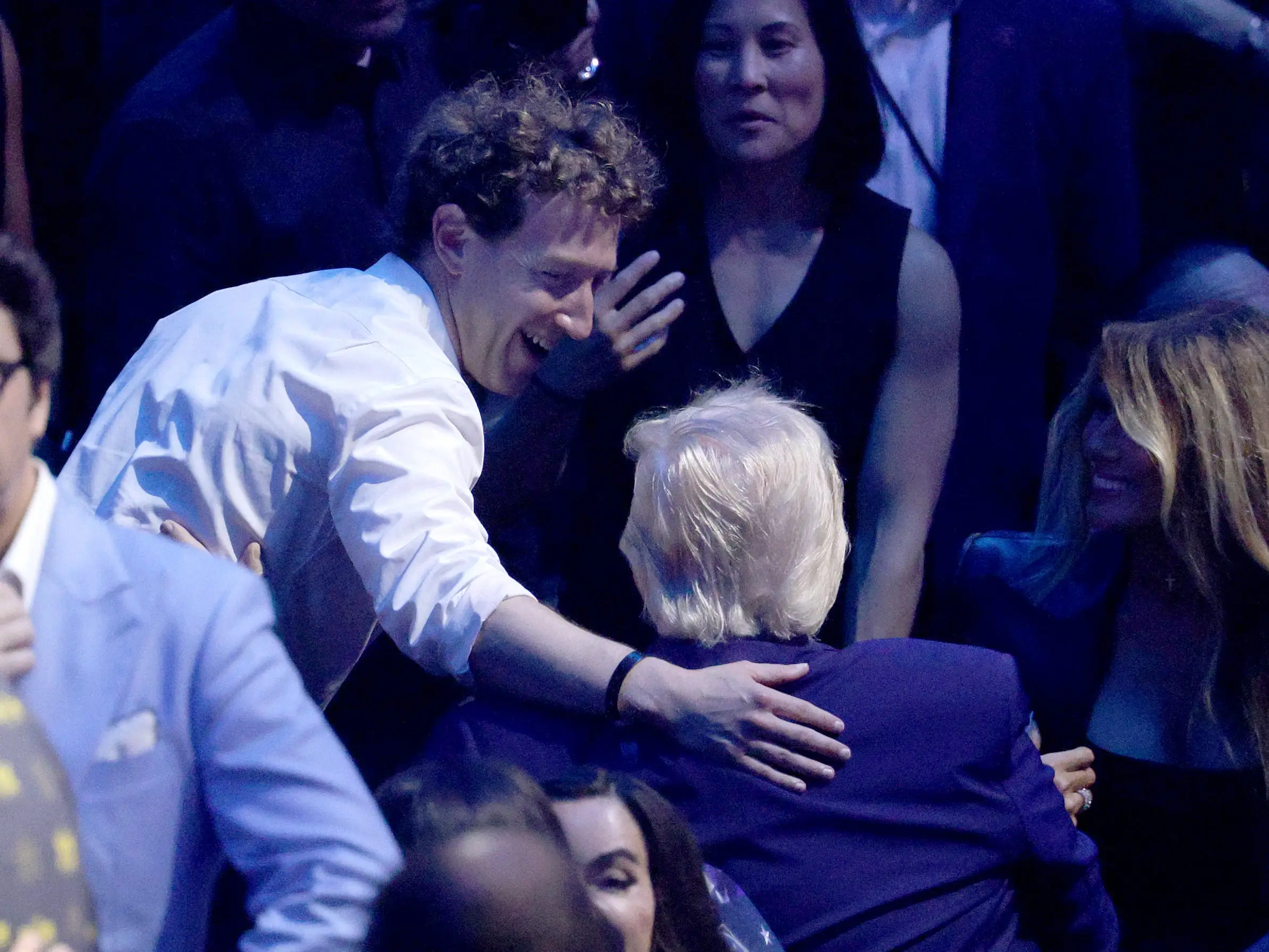 Mark Zuckerberg holding an arm to Trump's back as the two chat