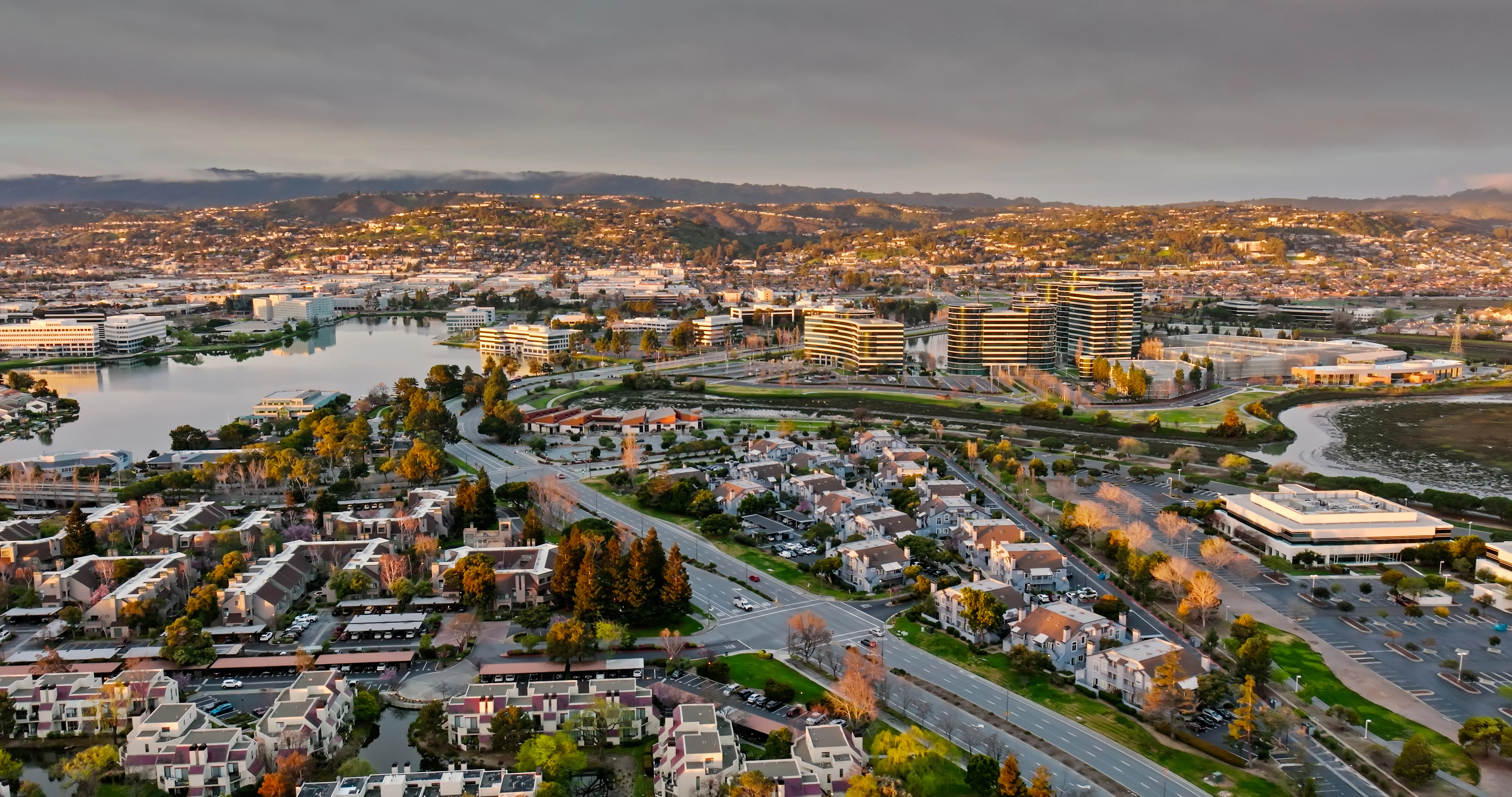 Aerial shot of a tidal inlet surrounded by commercial office parks and suburban housing in Redwood City, California.