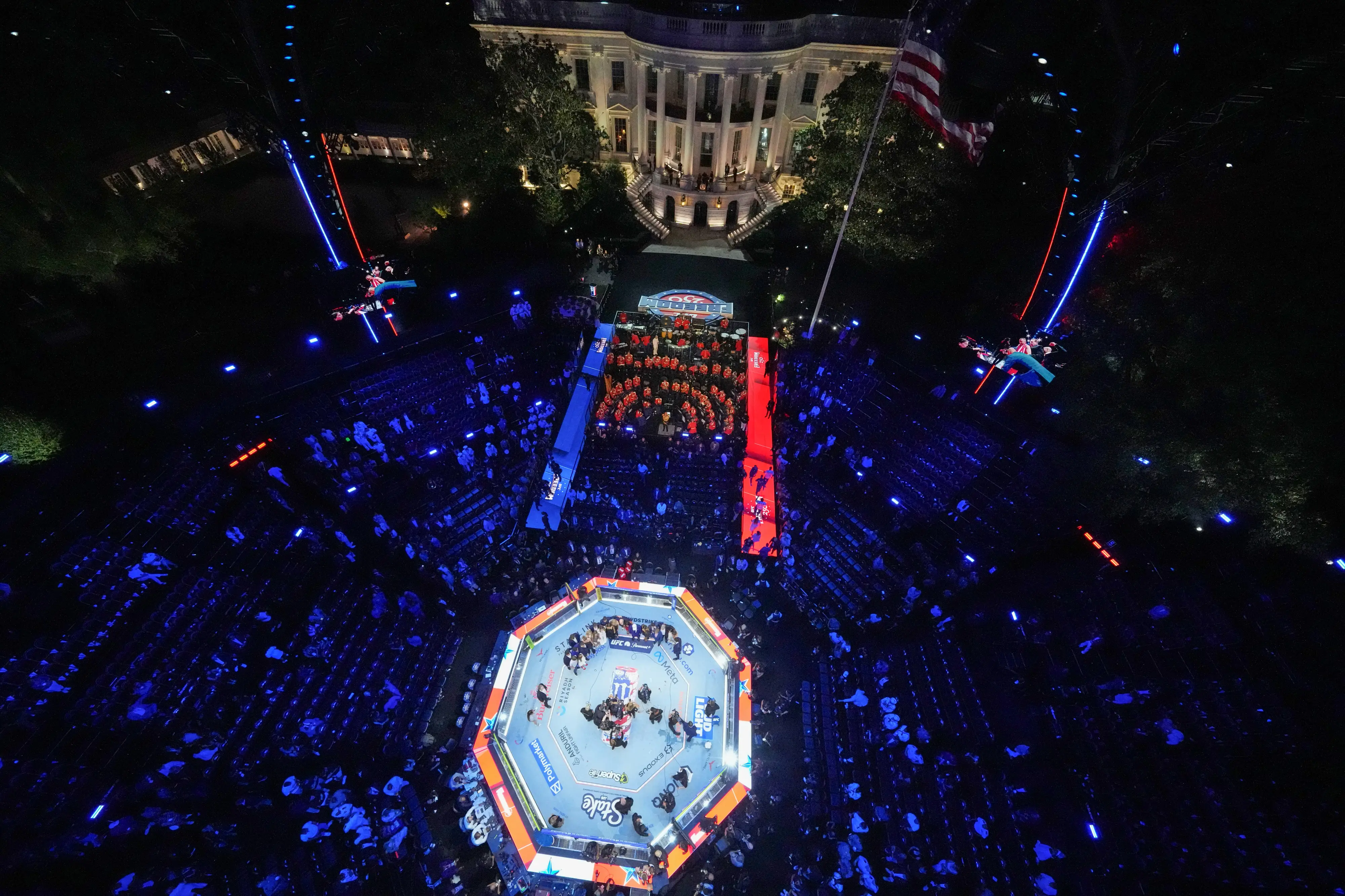 Overhead shot of the White House and the UFC ring set up on the lawn at night lit with blue and red lights.