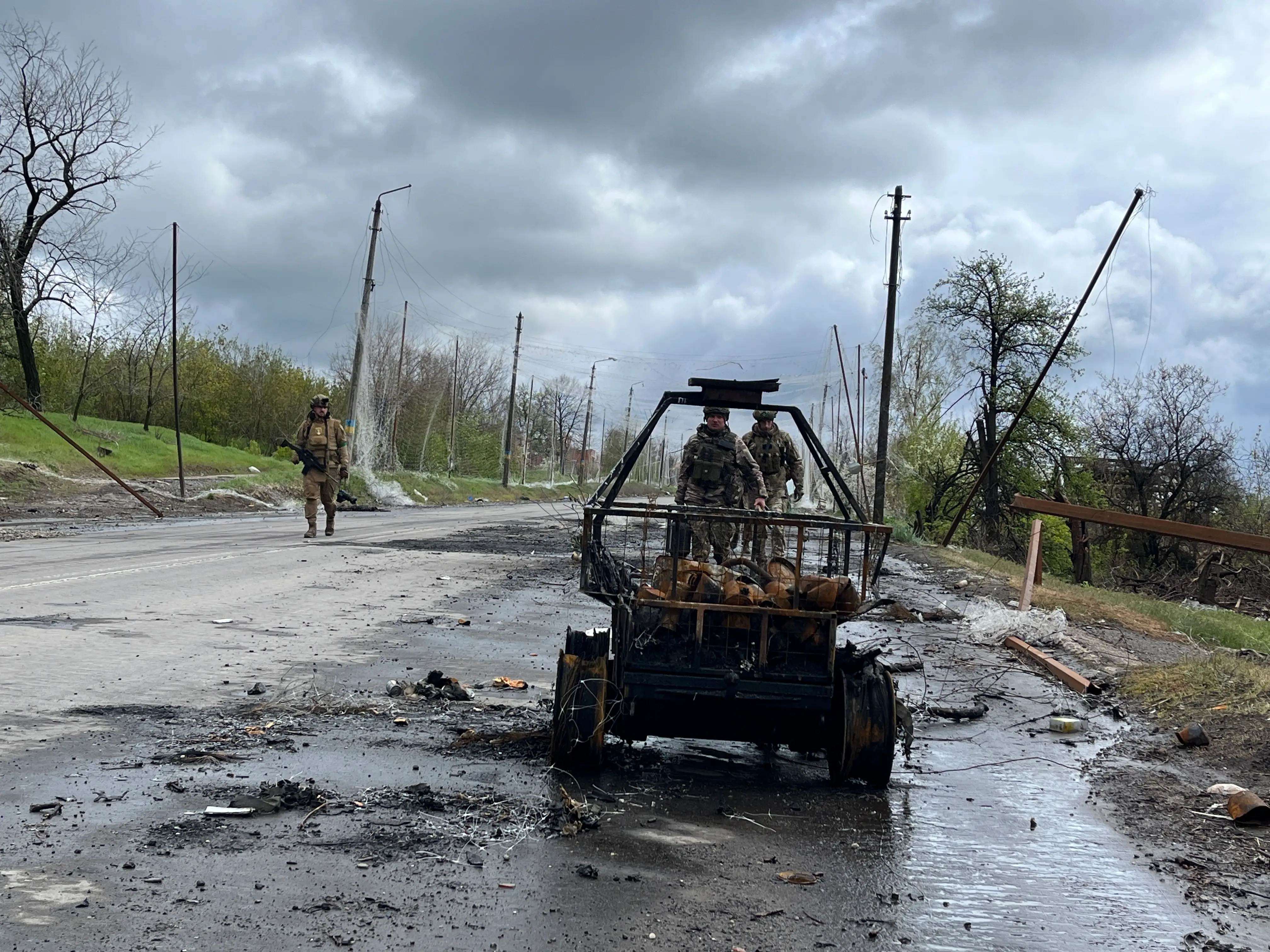 Ukrainian soldiers walk past a burned unmanned ground vehicle wreckage along the Kostiantynivka-Kramatorsk road on April 24, 2026, in Donetsk Oblast, Ukraine.