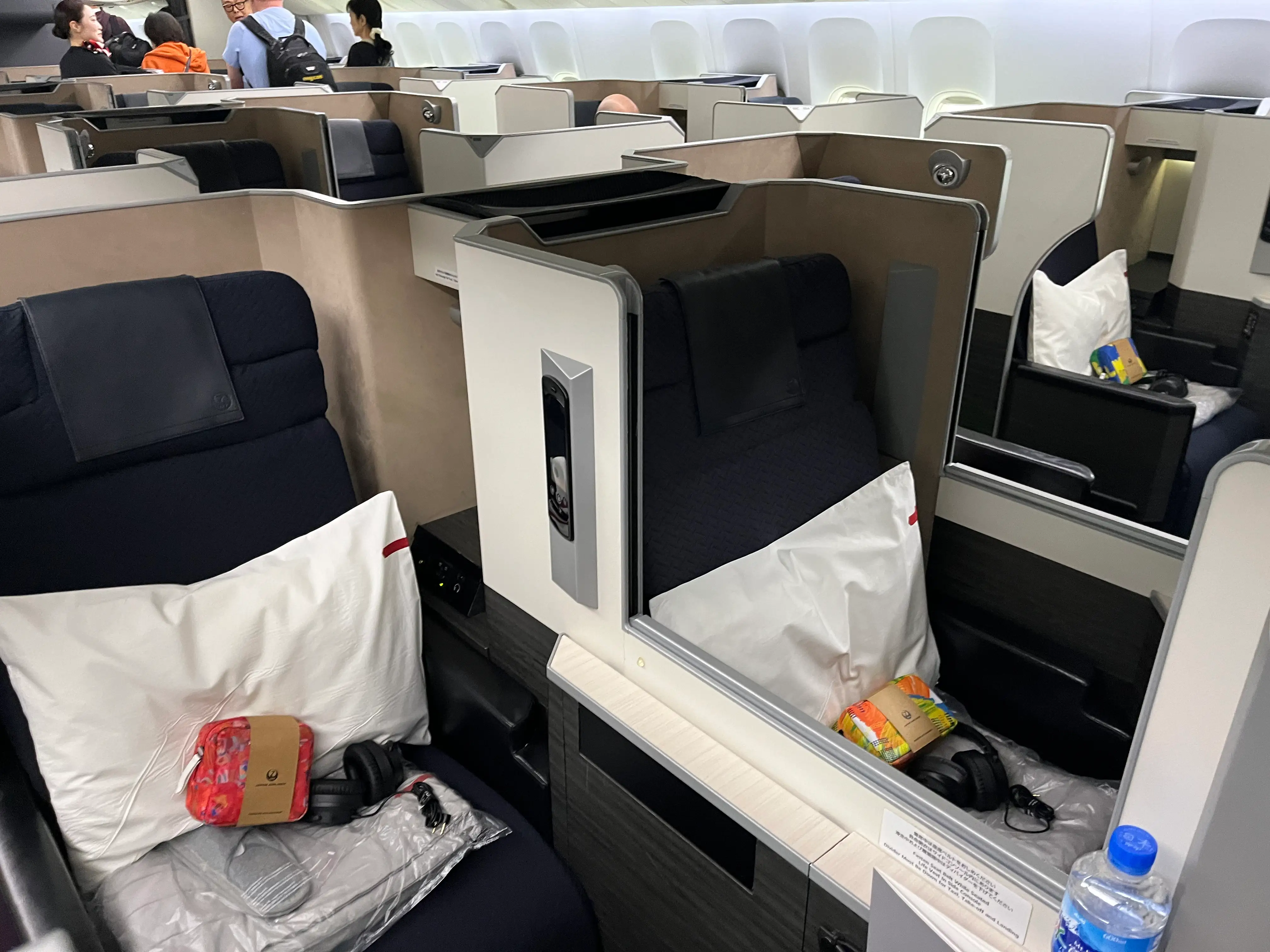 Business class seats on Japan Airlines flgiht with amenity bags, pillows, headphones on seat
