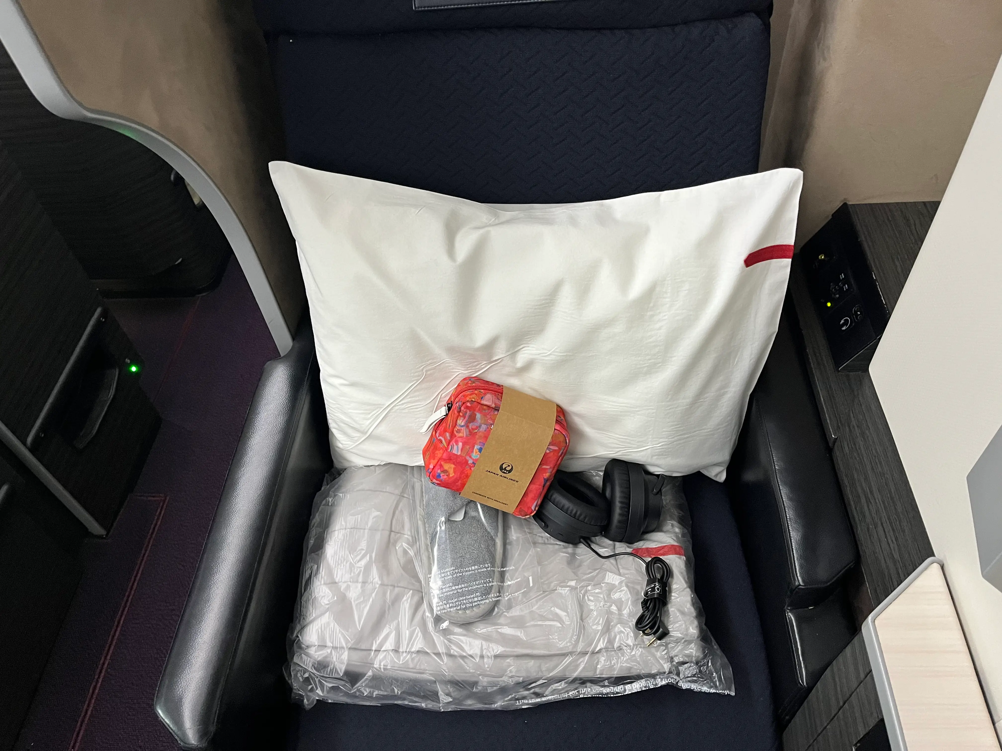 Pillow, amenity bag, slippers, headphones on plane seat
