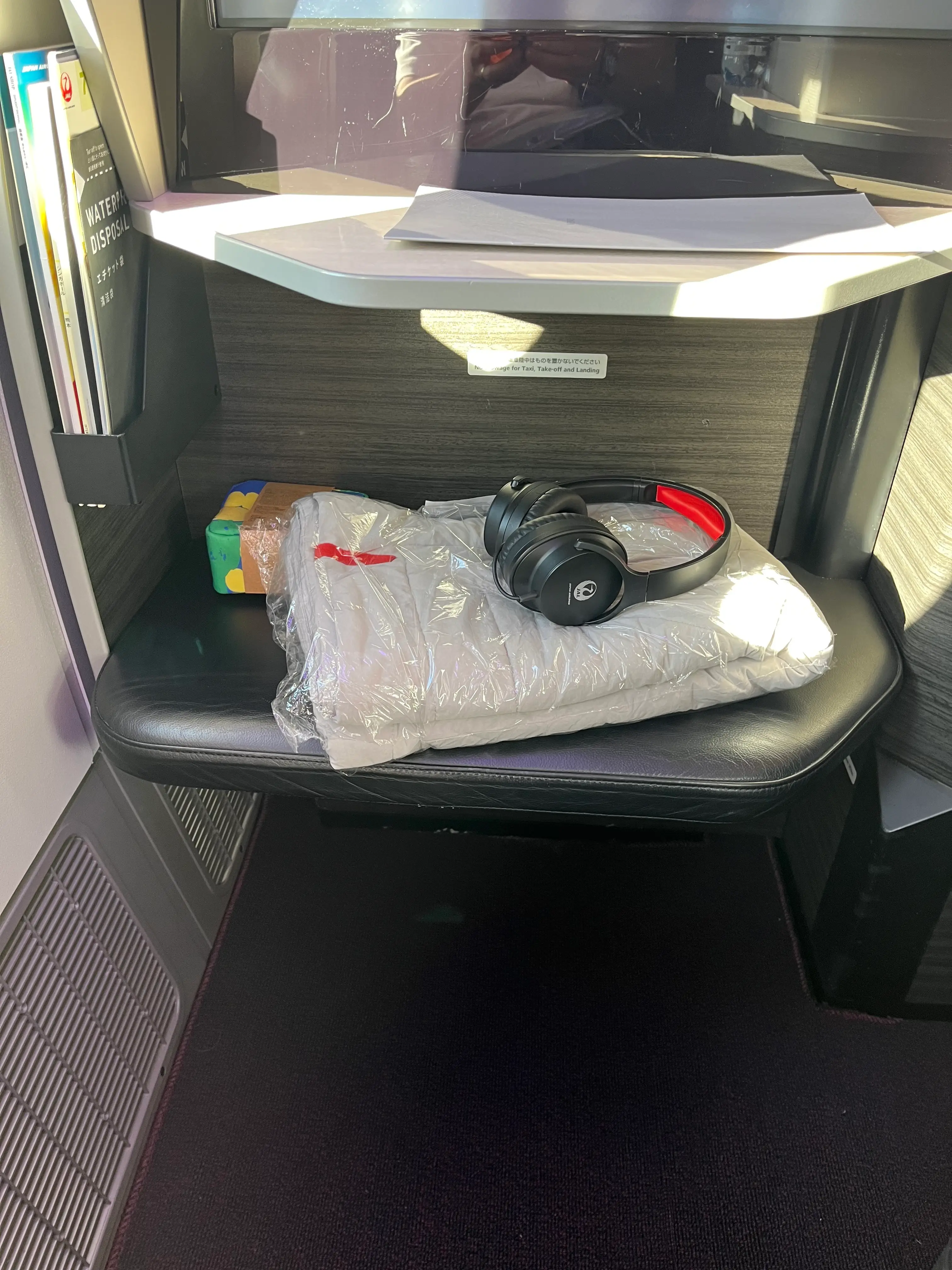 View of legroom, shelf with headphones on it in Japan Air business class