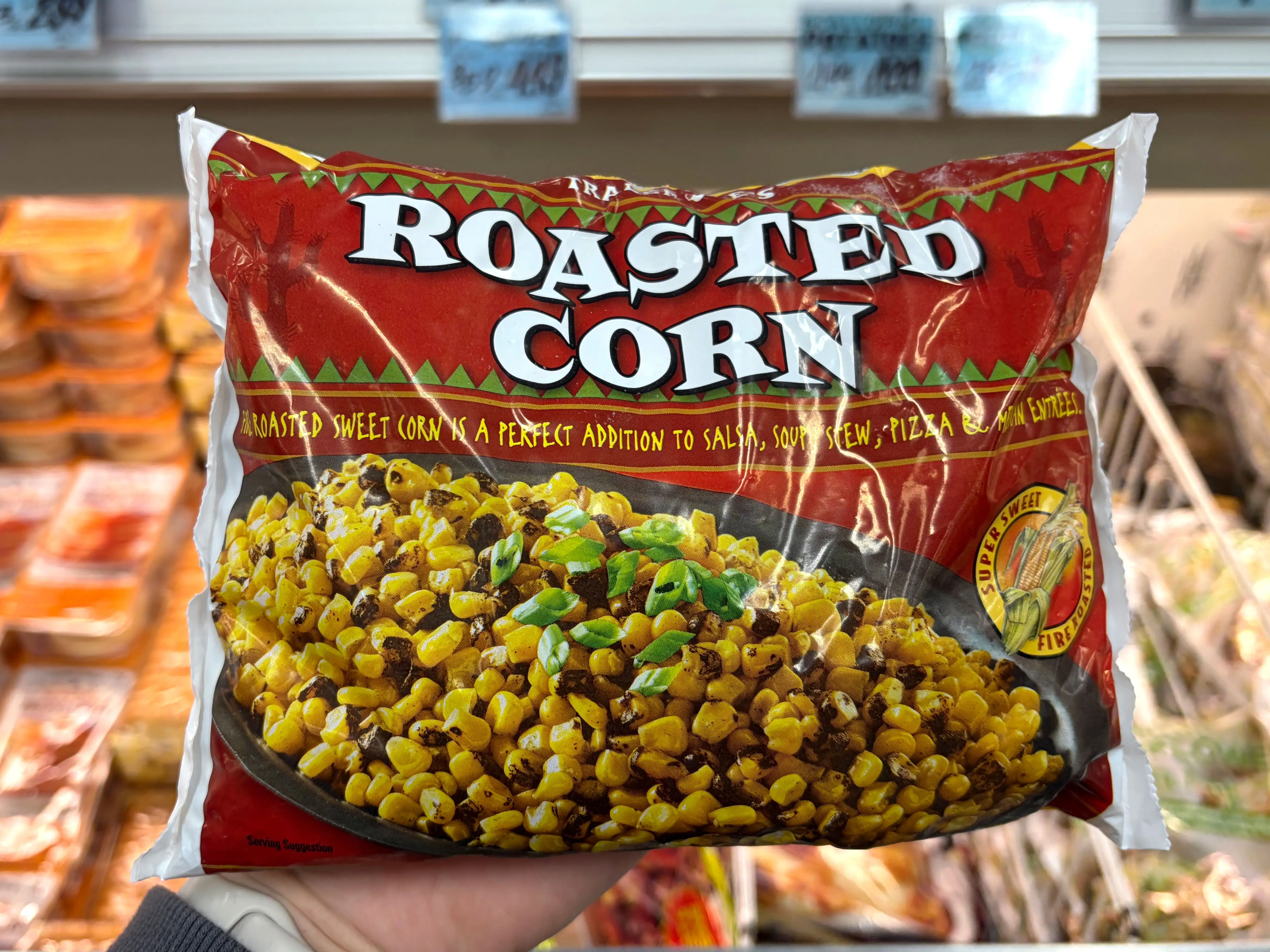 A hand holding a bag of Trader Joe's roasted corn.