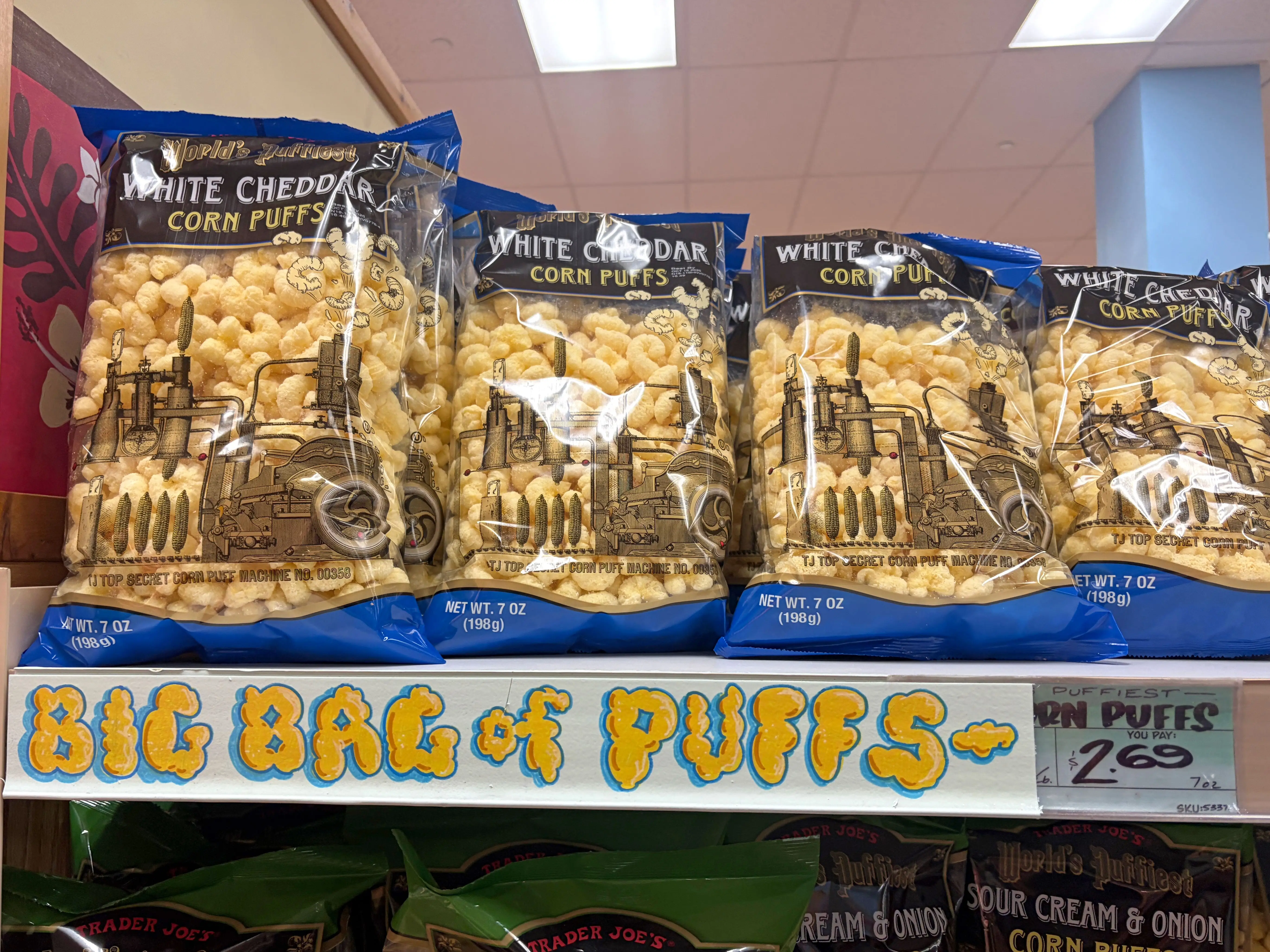 Bags of white-cheddar corn puffs on a shelf at Trader Joe's.