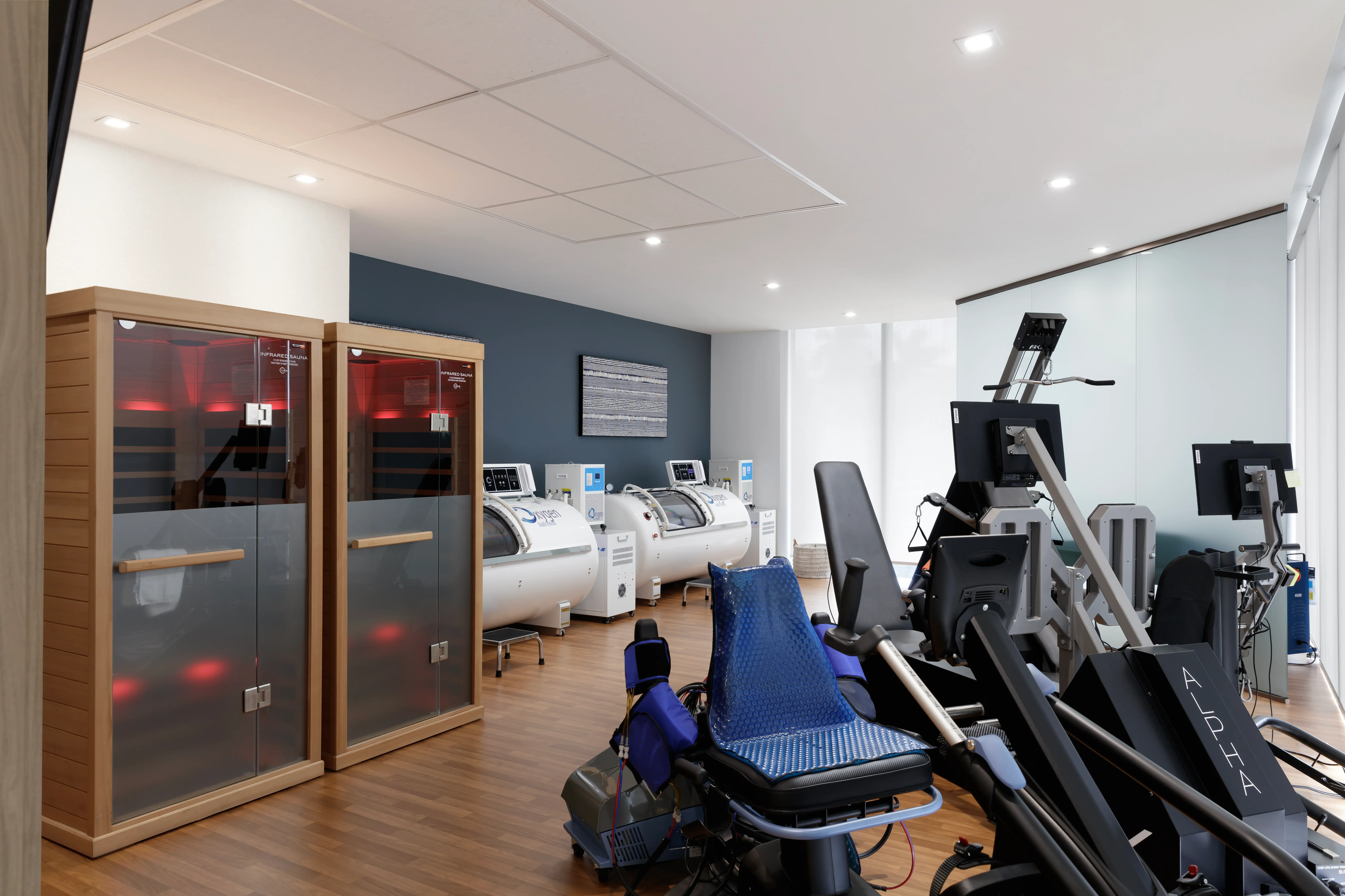 Infrared saunas and hyperbaric oxgen chambers line one side of the room opposite an array of recovery machines.