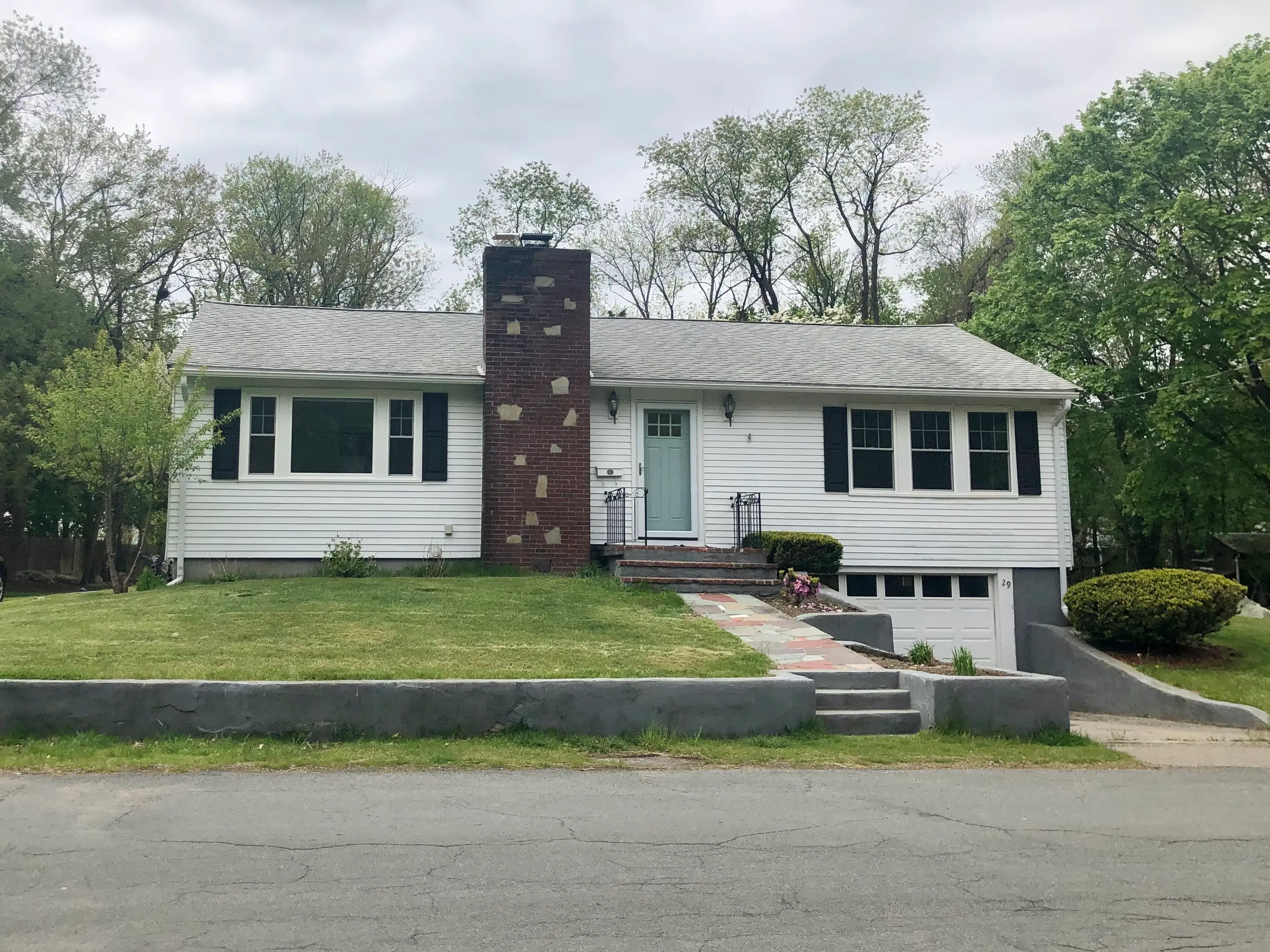 A white ranch house with a large chimney and black shutters.