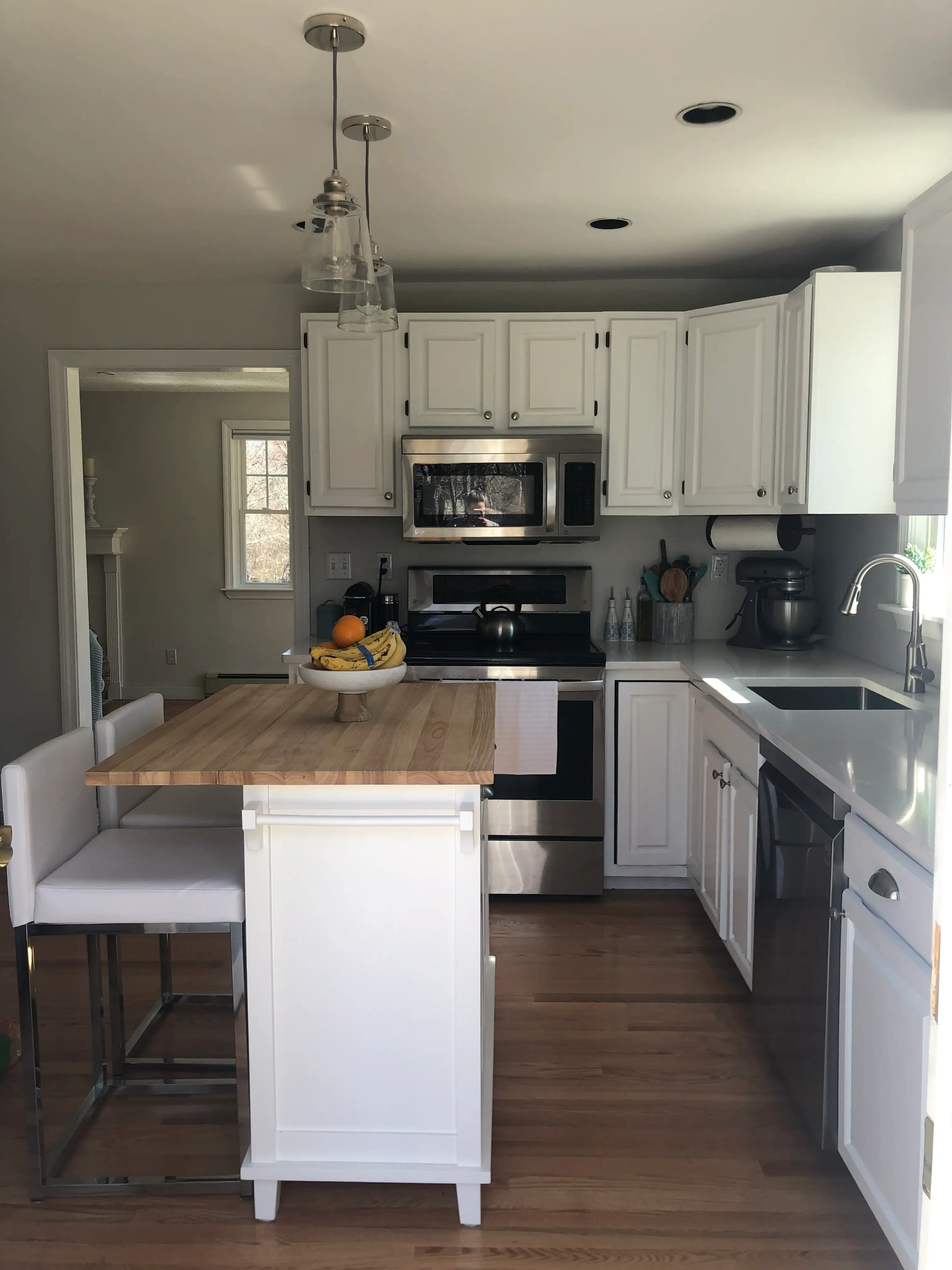 A kitchen with white cabinets and a butcher block island.
