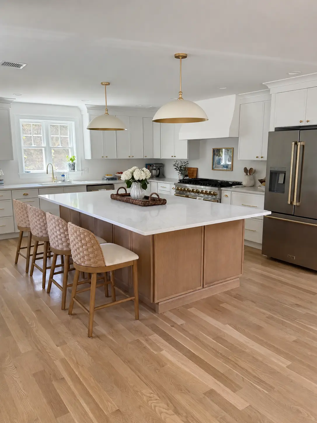 A large kitchen with white cabinets, stainless steel appliances, and a massive island.