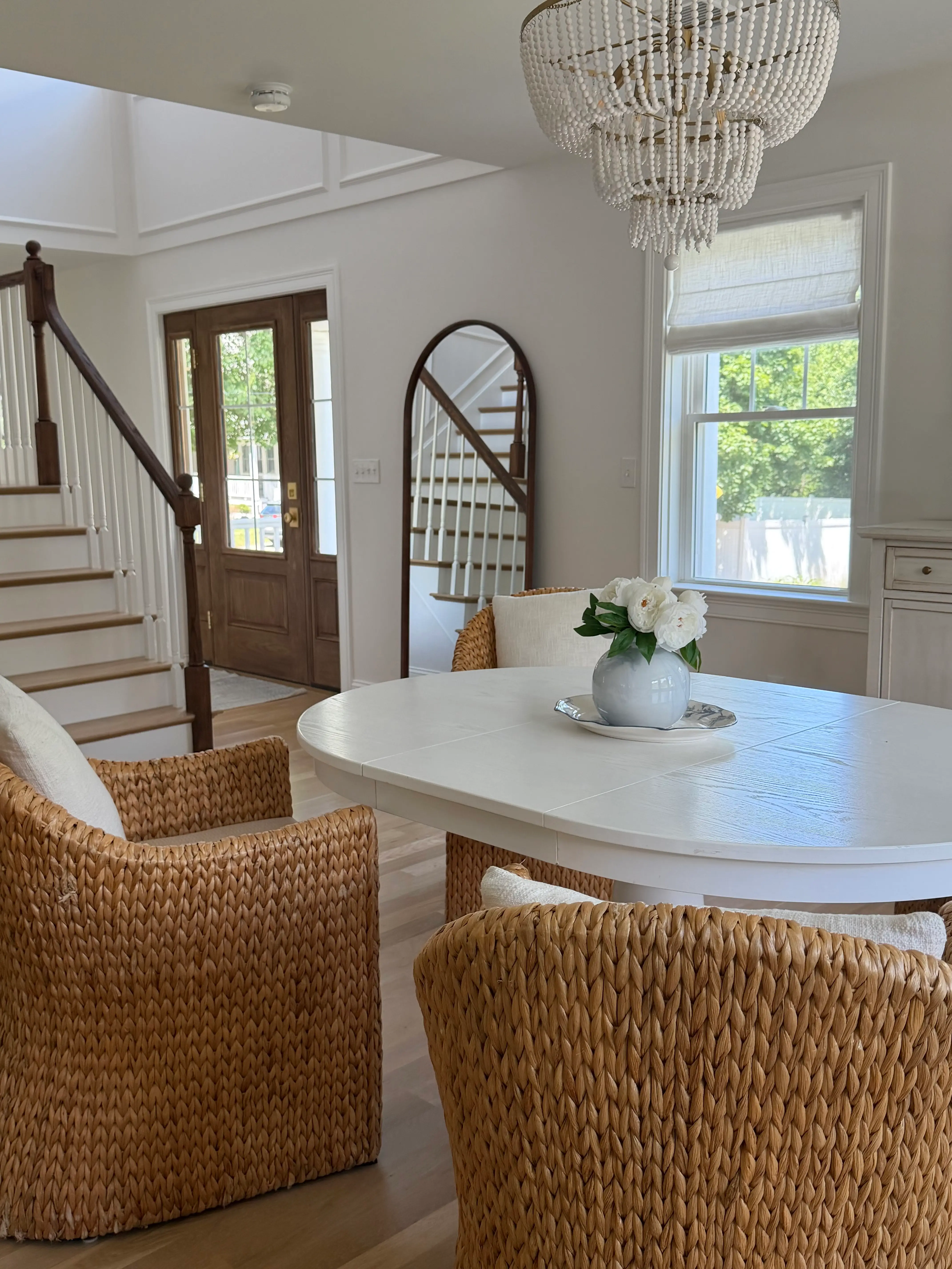 A living room with a large chandelier. A doorway and staircase sit nearby.