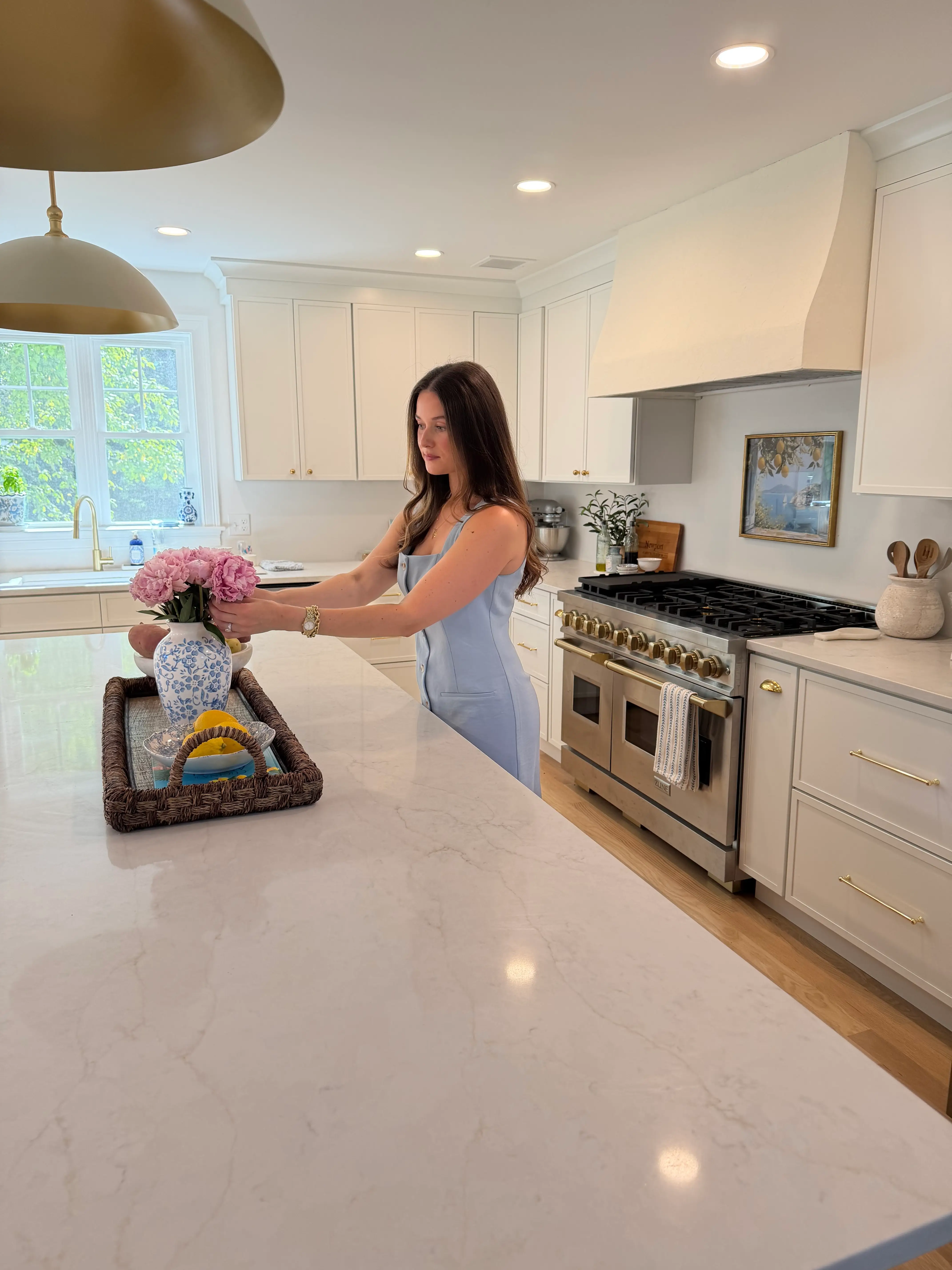 A woman adjusts flowers in her large kitchen.