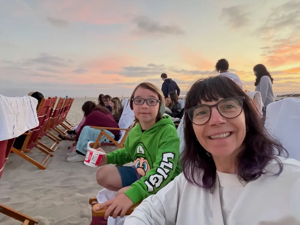 The author traveling with her child at a beach movie night.