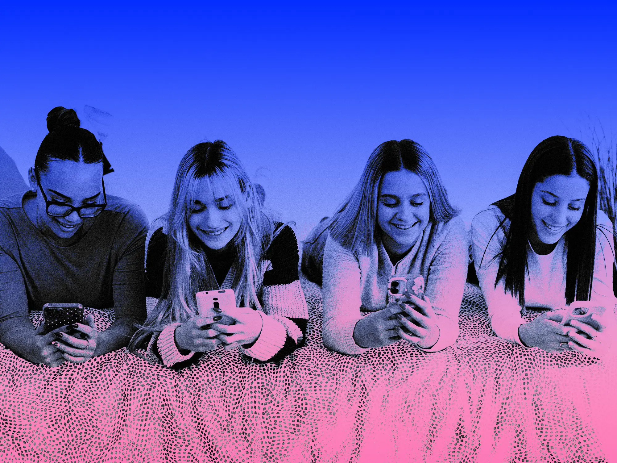 Four teenage girls sitting together and scrolling on their cell phones.