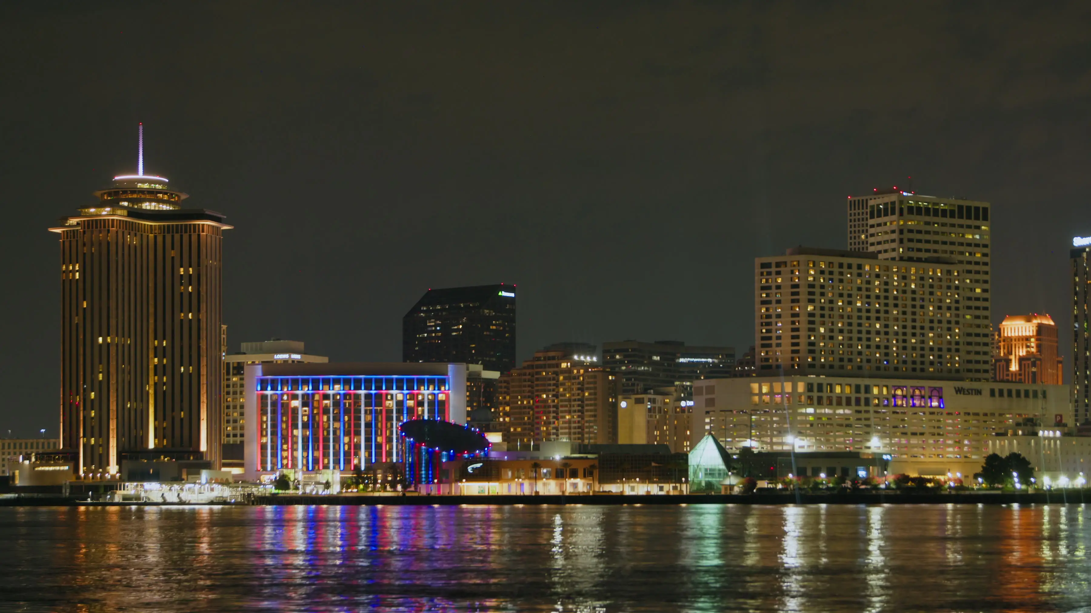 New Orlean skyline at night with a building lit up red, white, and blue.
