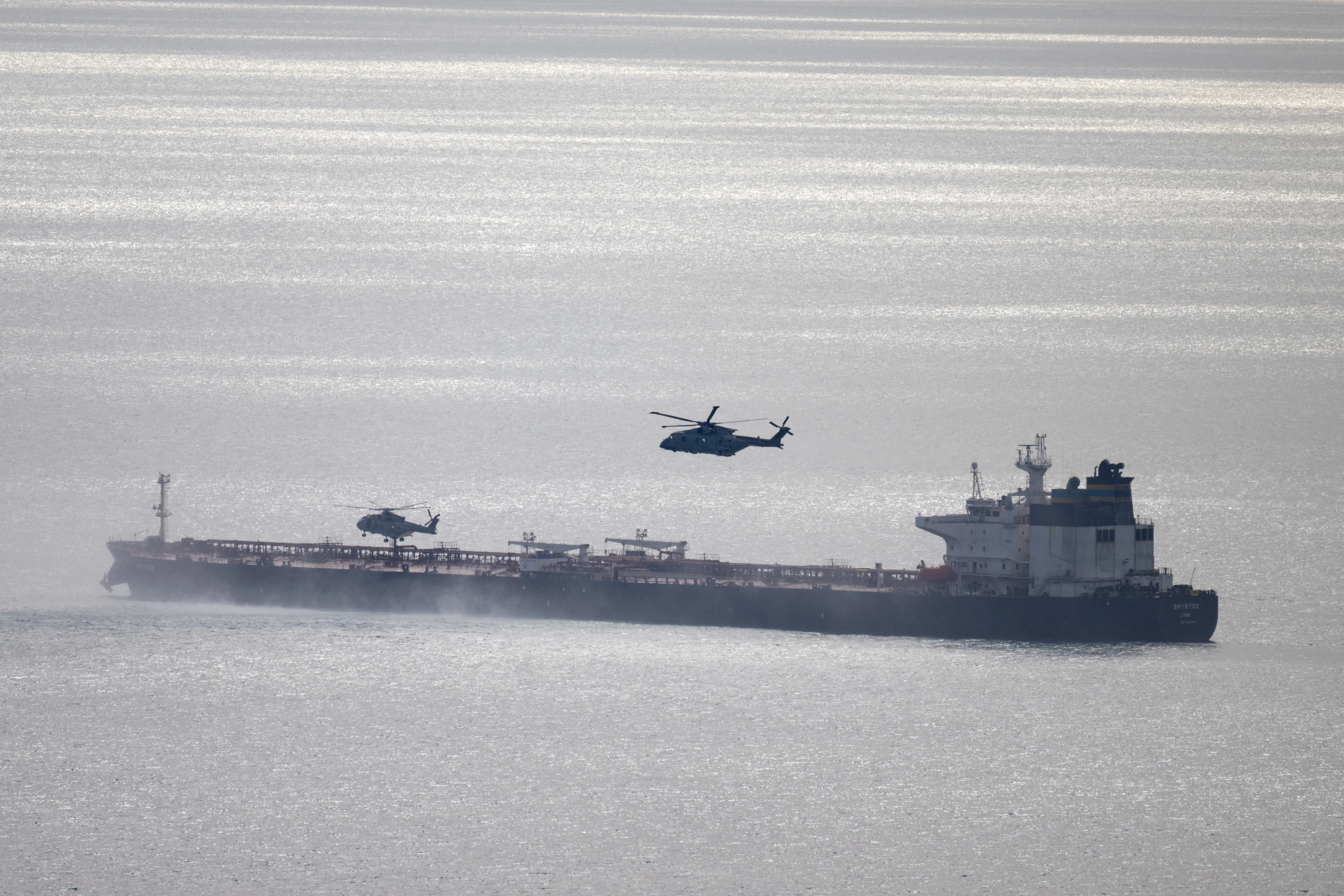 Military helicopters are seen approaching an oil tanker.