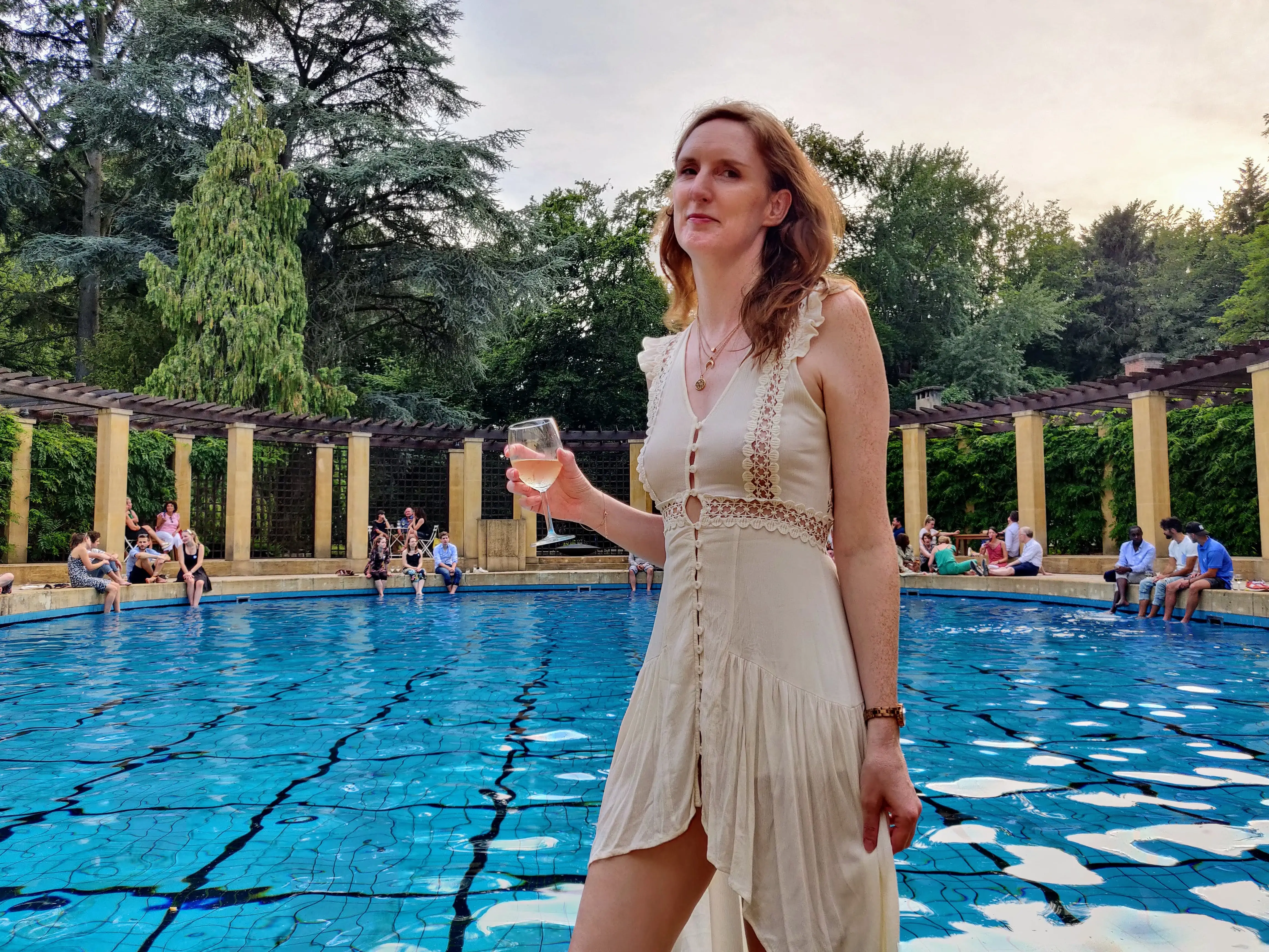 A woman holding a glass of wine at an after-work summer event at Villa Empain in Brussels, Belgium.