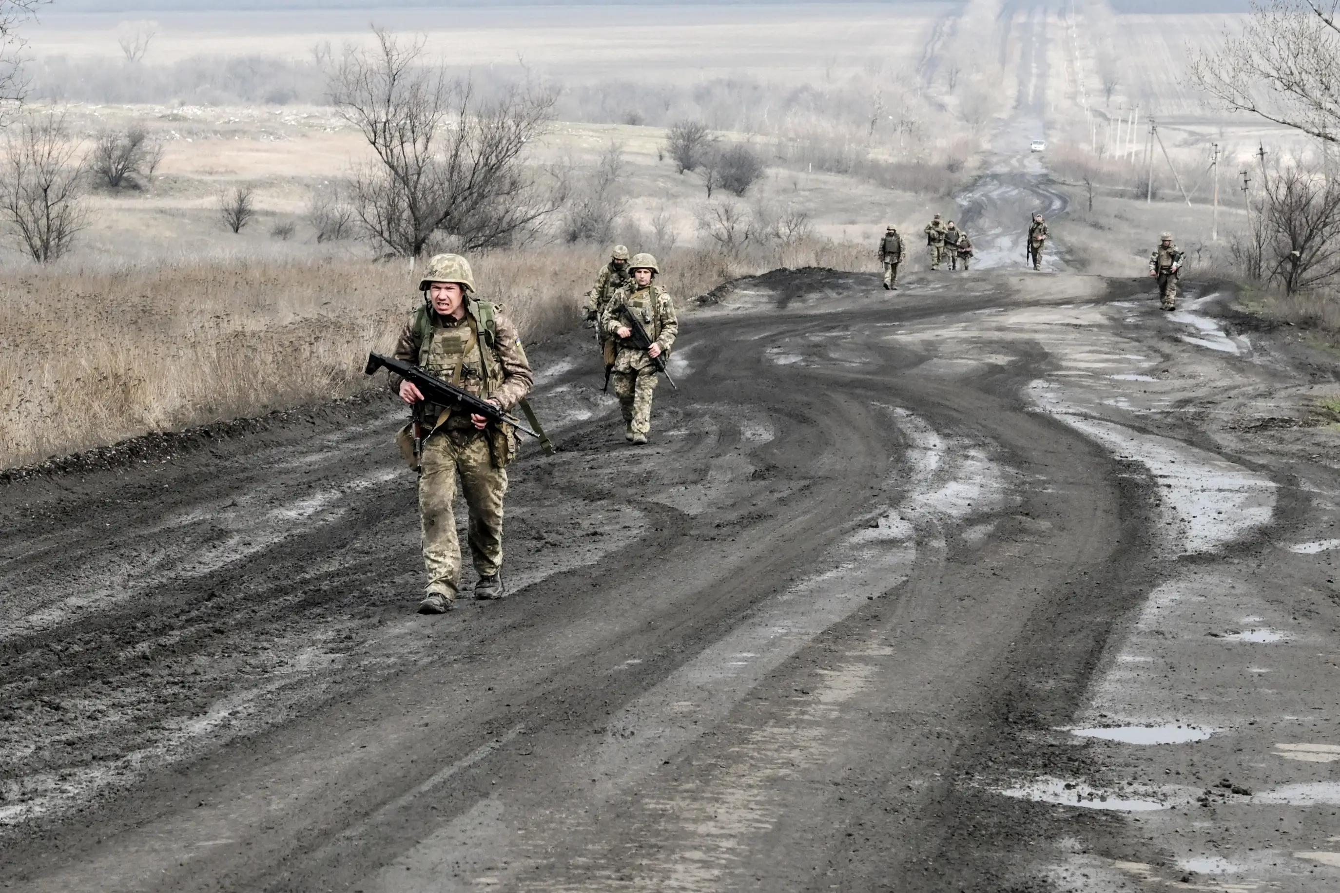 Soldiers from the 141st Mechanized Brigade of the Ukrainian Land Forces, armed with rifles, walk along a road on the front line, March 19, 2026.