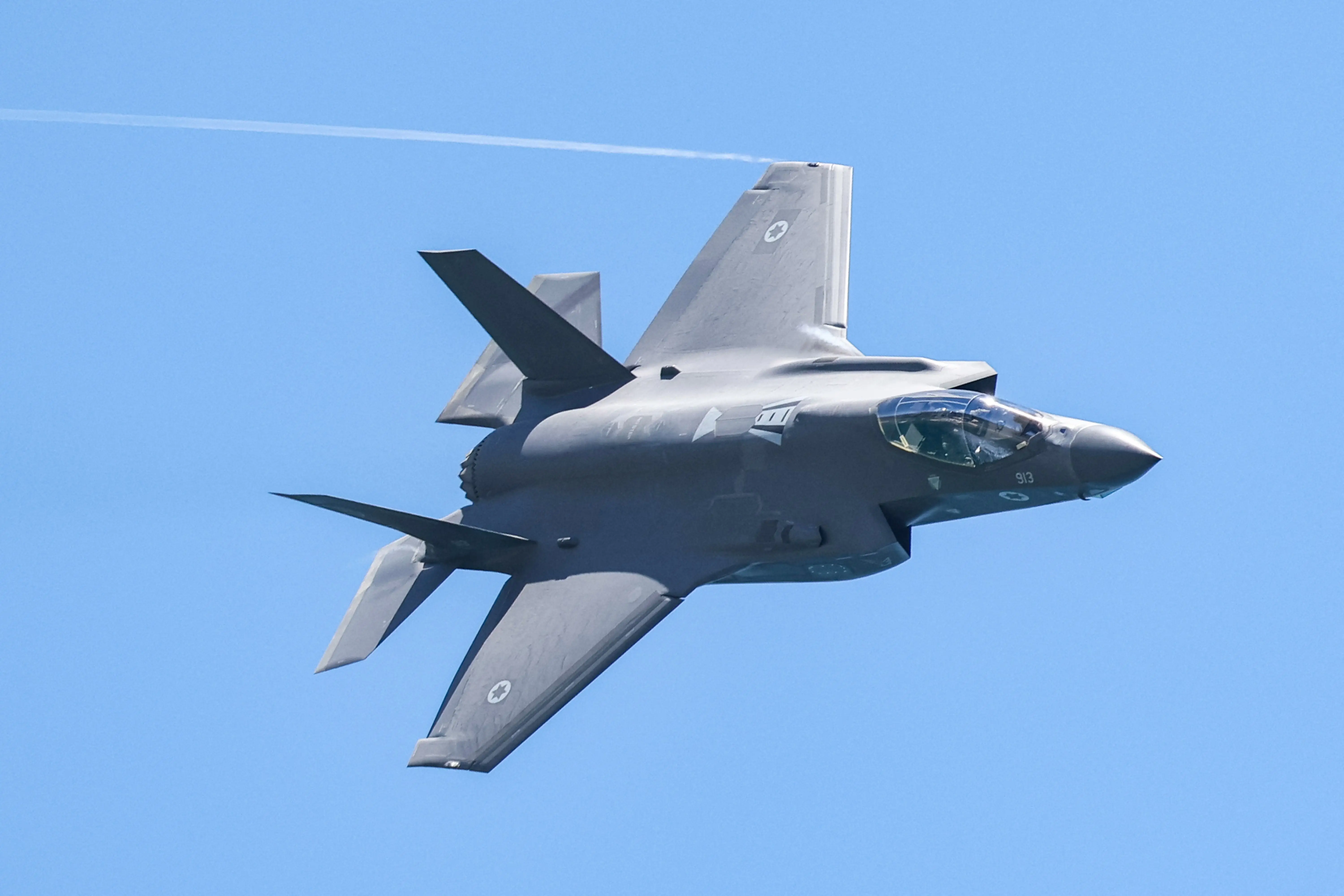 A grey jet flying on its side in a blue sky