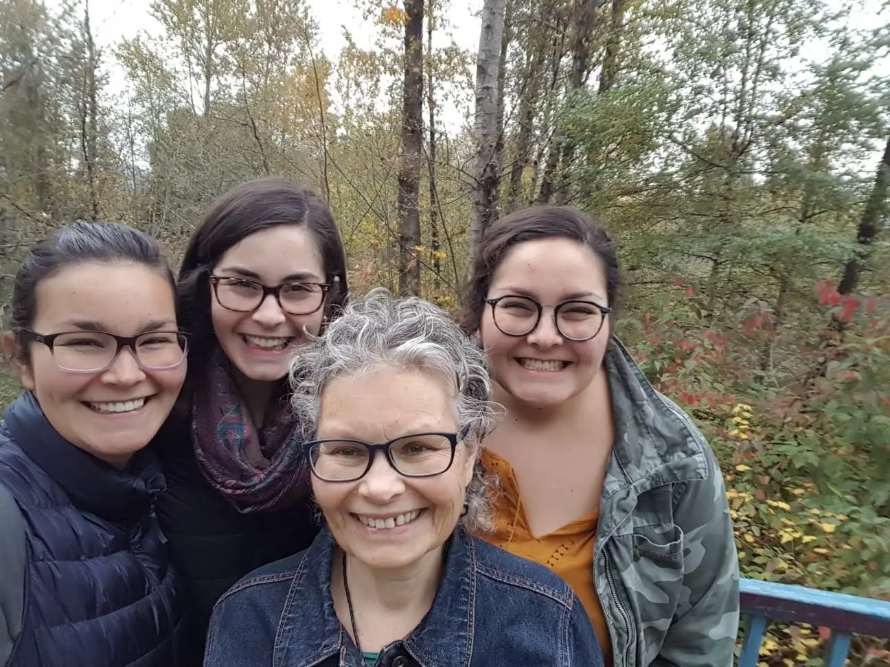 The author with her mom and sisters pose outside with trees behind them.