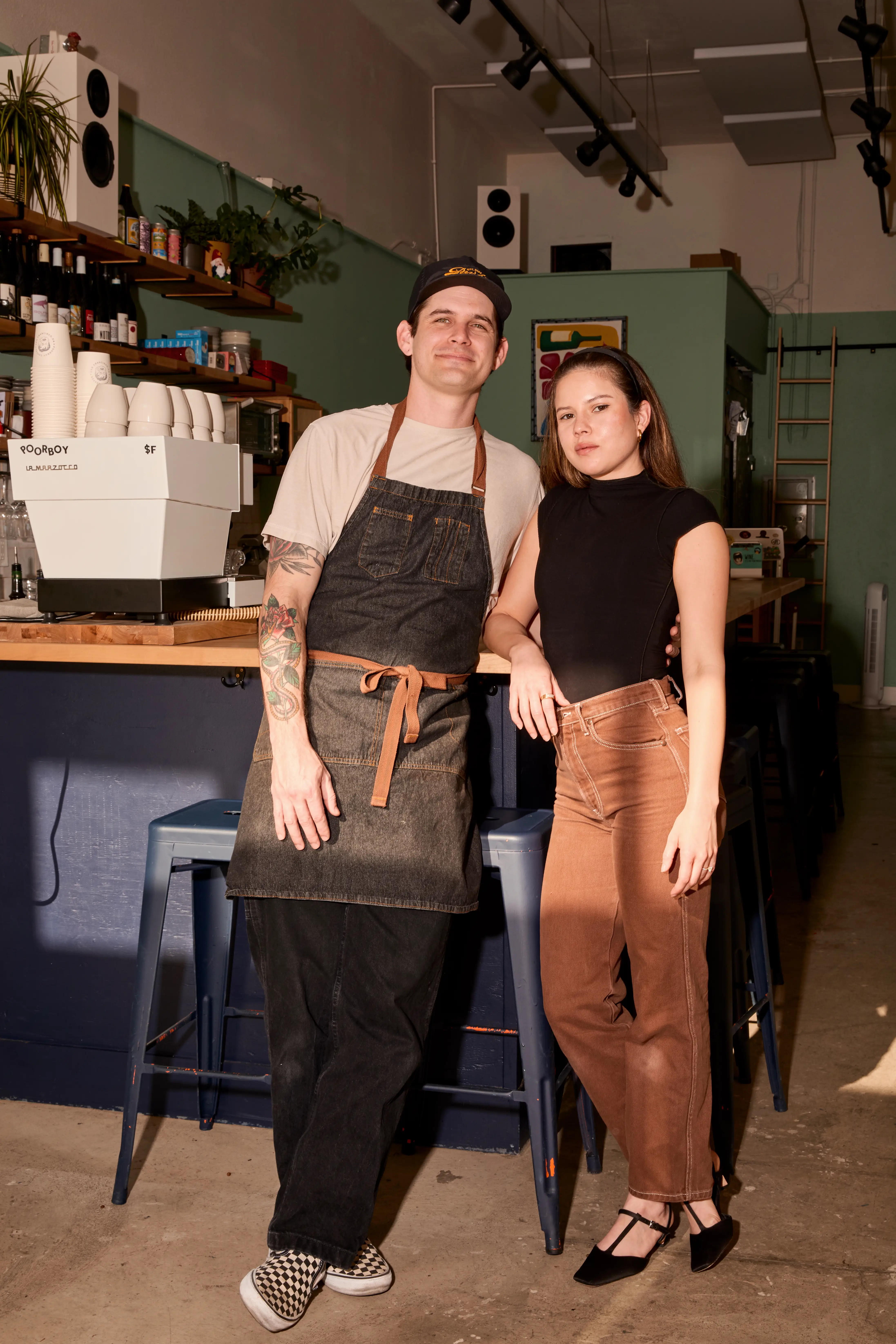 Brandon and Alexis, founders of Poorboy, stand in front of a coffee kitchen.