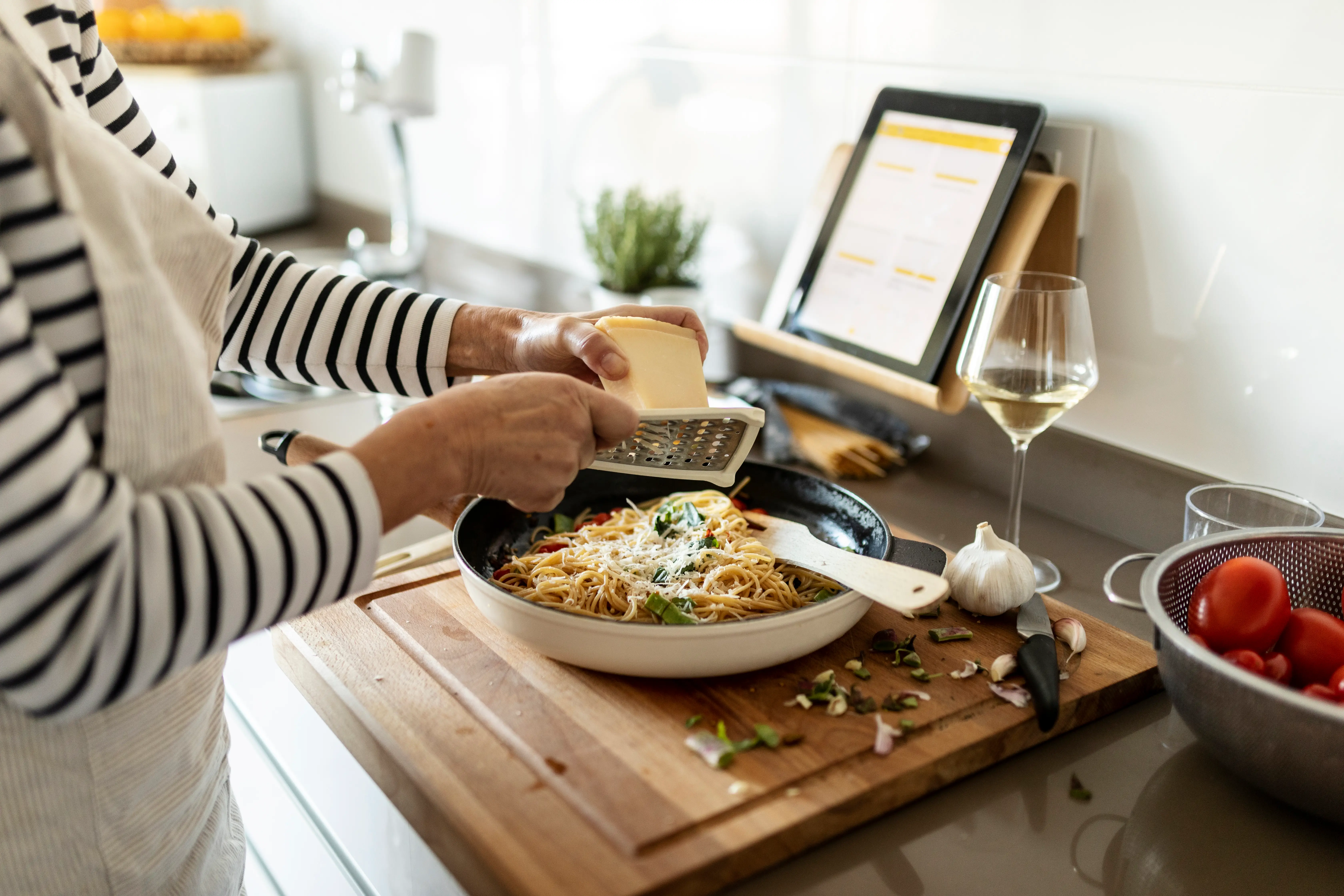 A woman puts the finishing touches on a pasta dish.