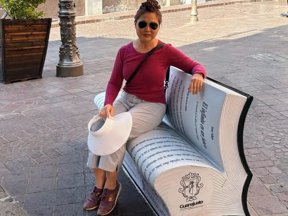 Woman sitting on book-shaped bench in Guanajuato Mexico
