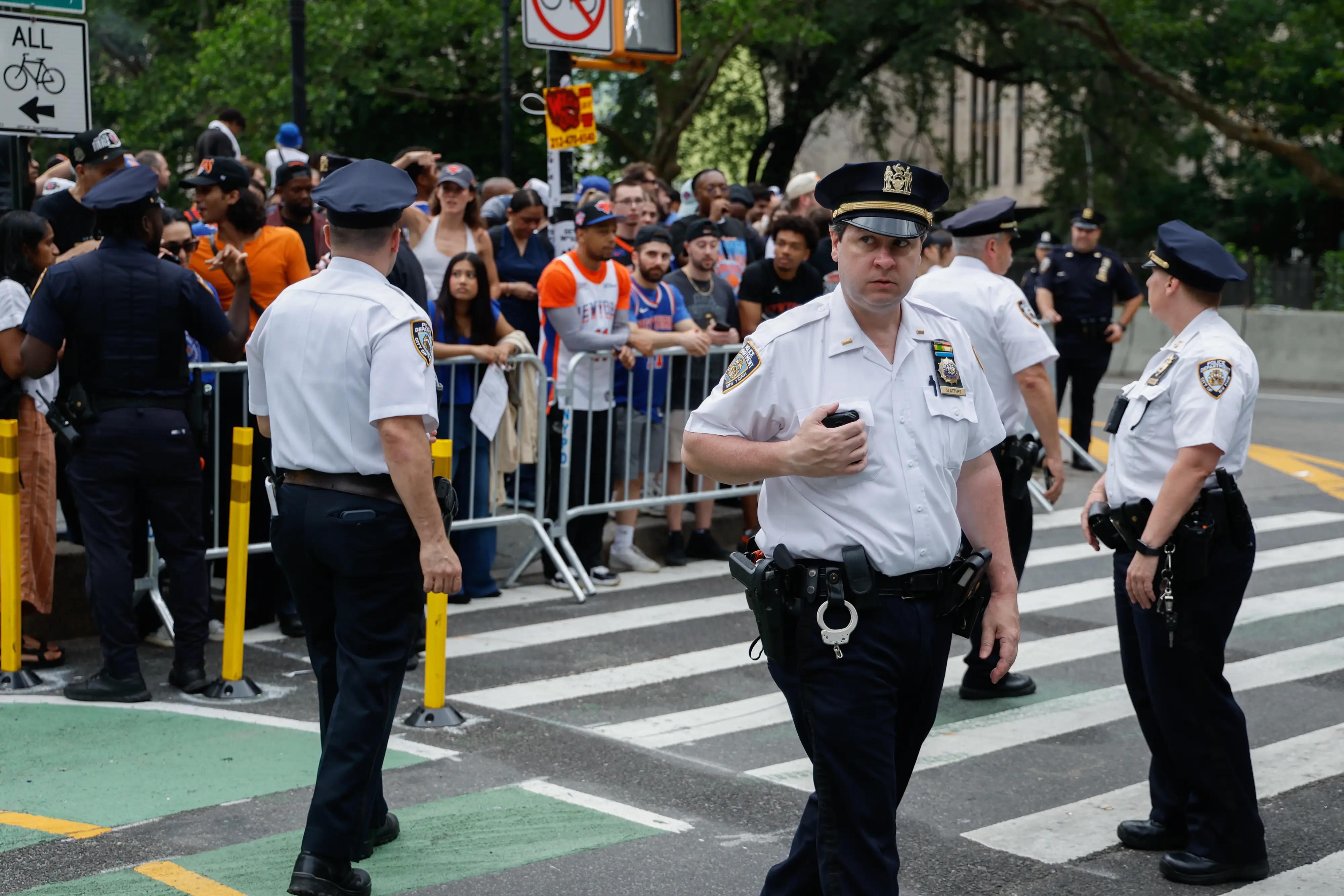 New York Police Department (NYPD) officers watch as fans arrive ahead of a ticker-tape parade to celebrate the New York Knicks' NBA Championship win