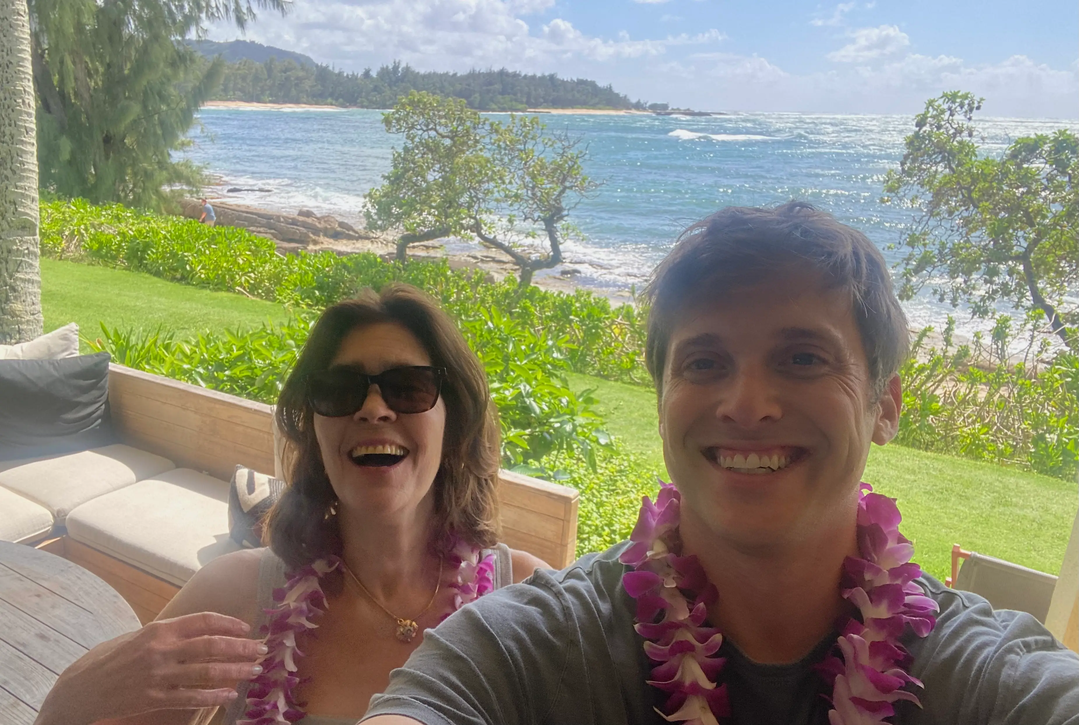Allison Tibaldi  and her son in front of the ocean in Hawaii wearing leis