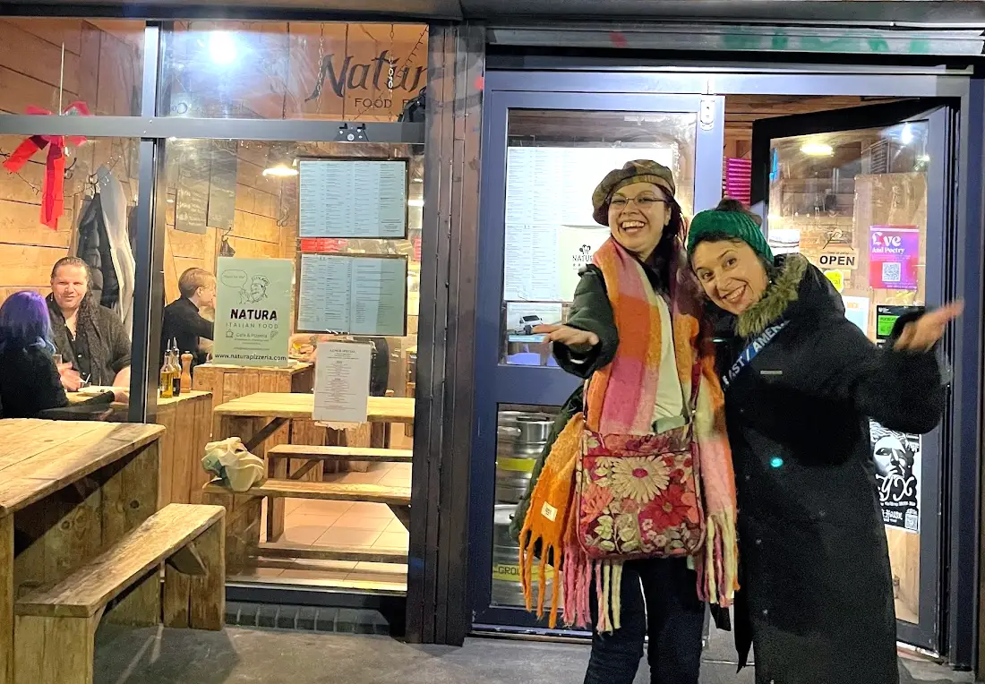 The writer and her friend standing in front of a restaurant in the nighttime.
