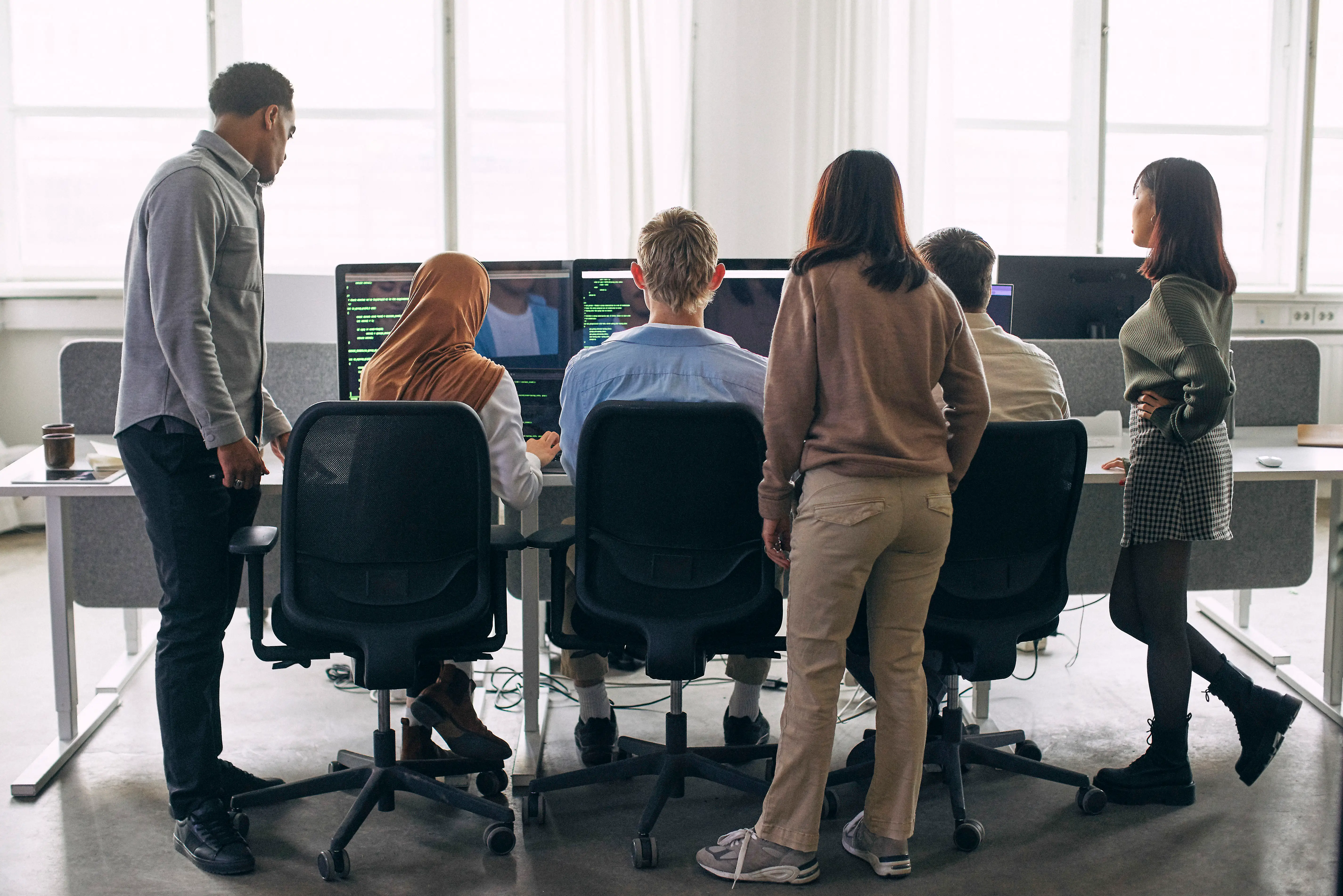 Male and female tech experts programming on computers at startup office