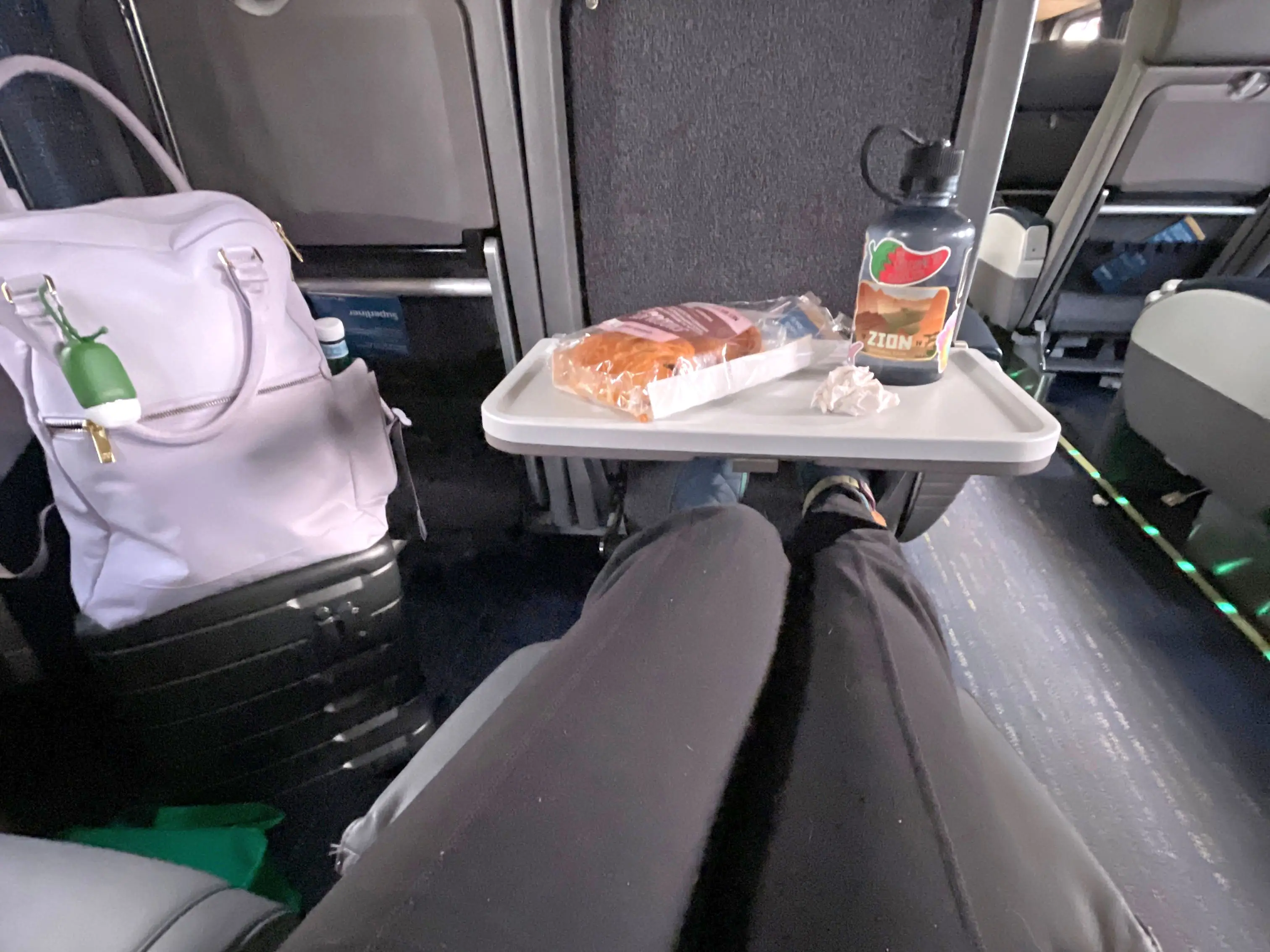 A woman stretching her legs out in a coach seat on an Amtrak train.