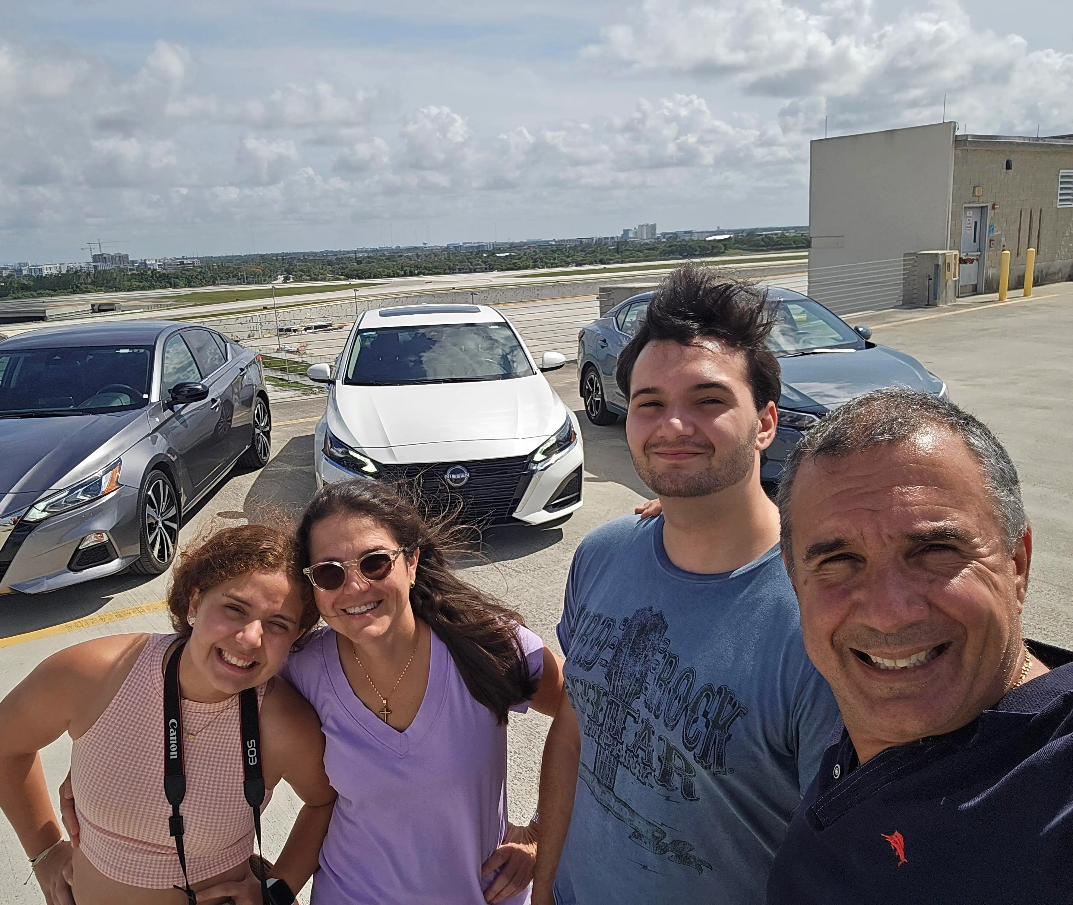 Gerardo Aletti and his family pose for a selfie in front of a few cars.