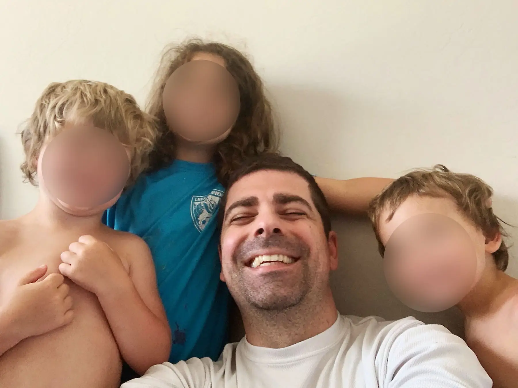 A man with three children, whose faces are blurred.