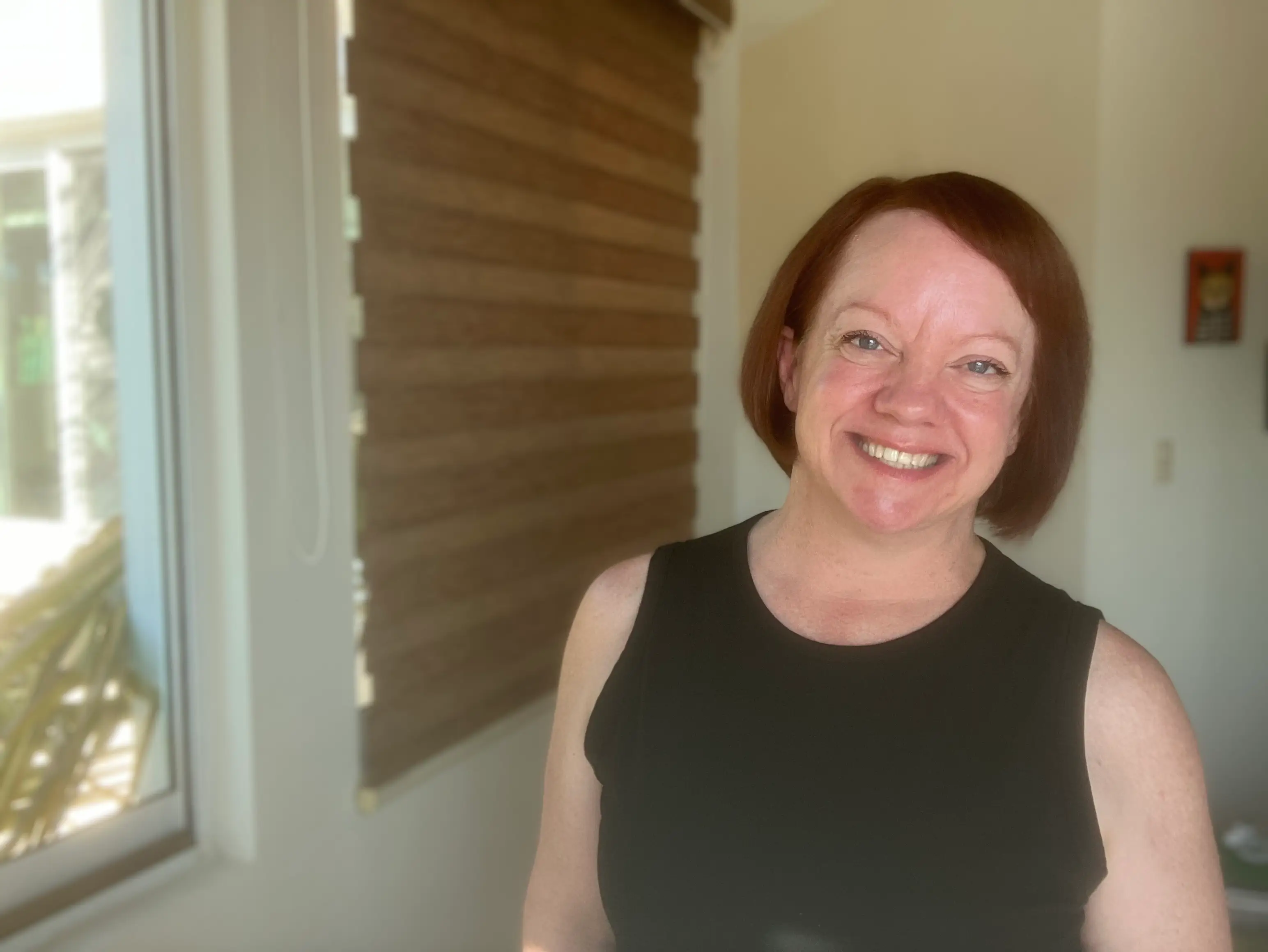 The author poses in front of a window.