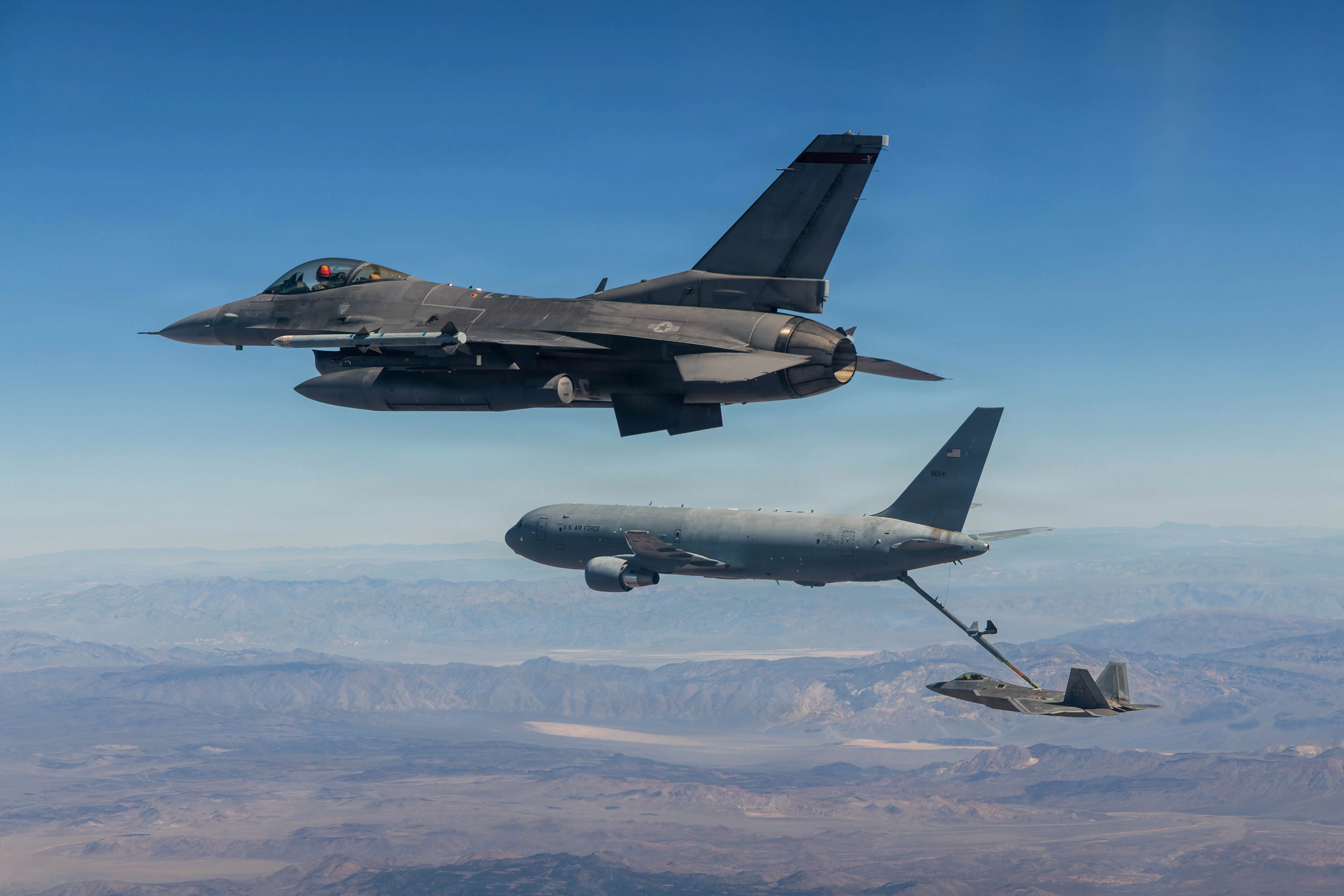 An F-22 flies alongside a KC-46 Pegasus tanker as the aircraft refuels a second jet over the Mojave Desert on March 3, 2026.