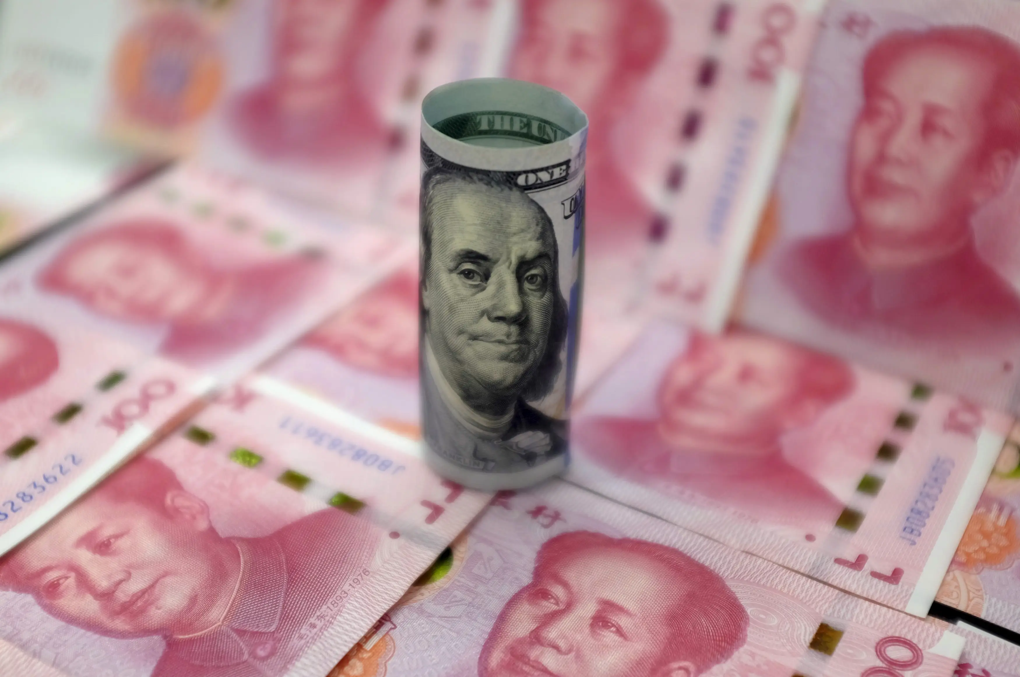 A US $100 banknote on top of Chinese 100-yuan banknotes depicting the late Chinese Chairman Mao Zedong.