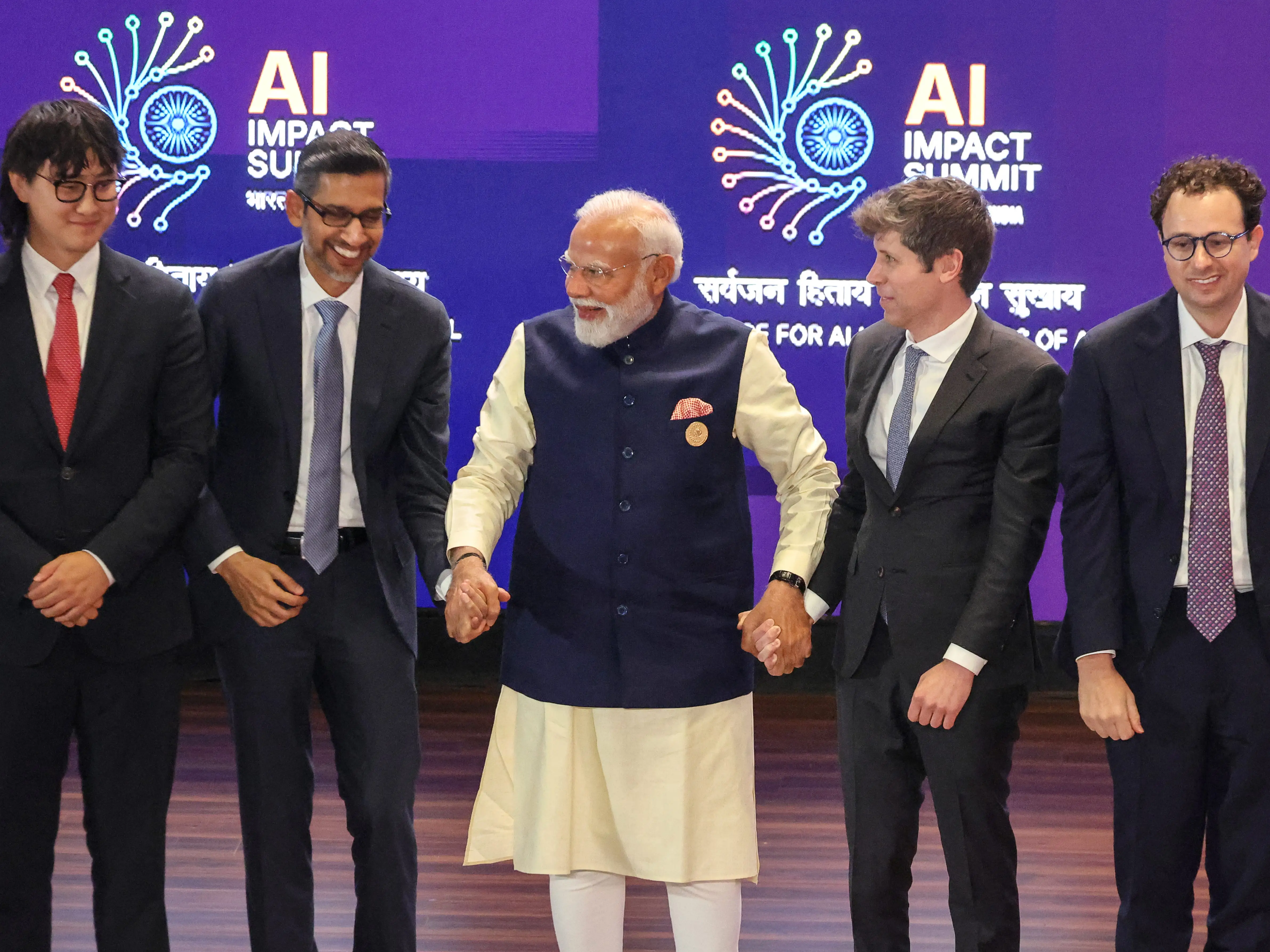 Indian Prime Minister Narendra Modi holds hands with Sundar Pichai and Sam Altman