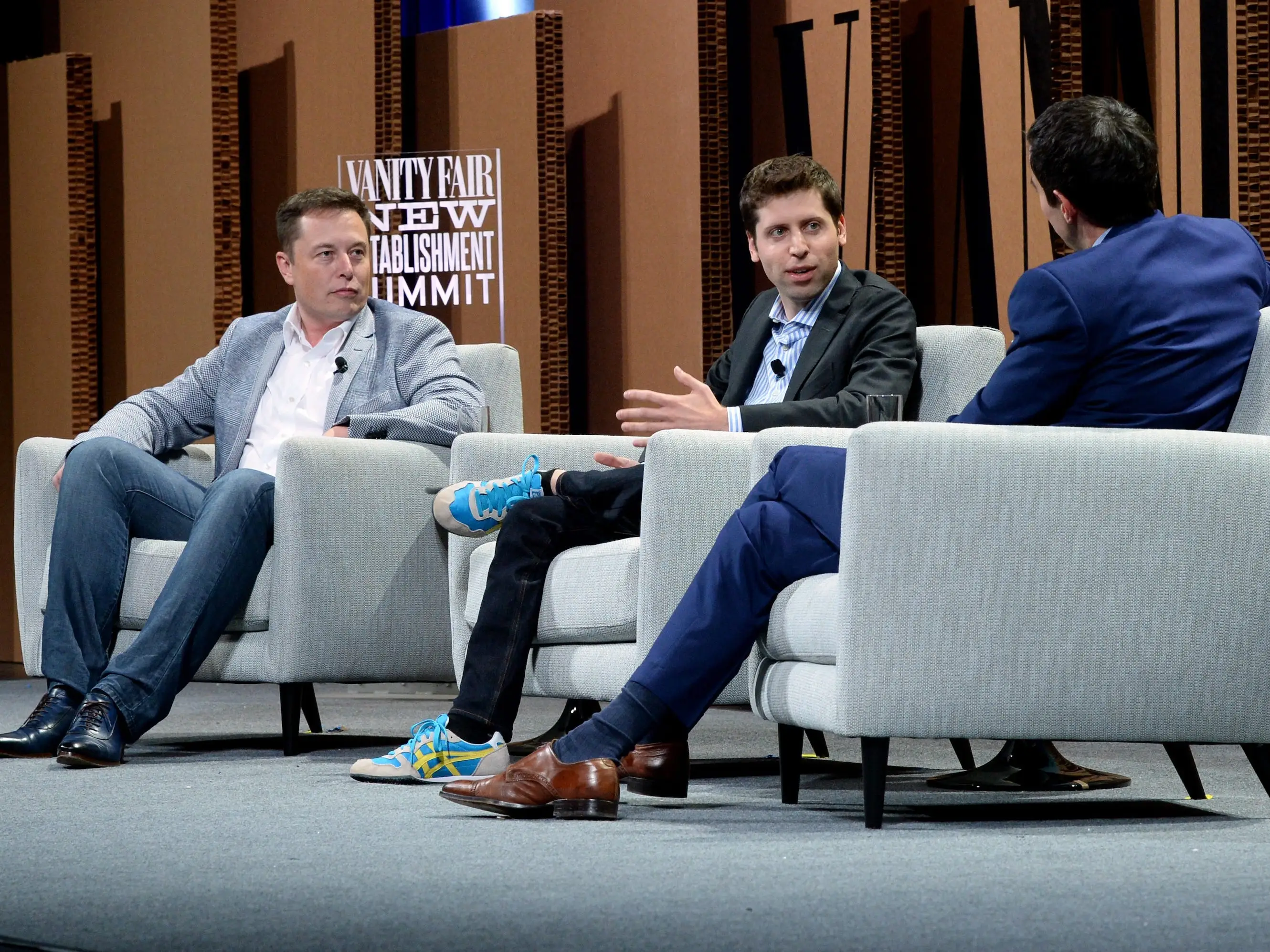 Elon Musk, Sam Altman, and the New York Times financial columnist Andrew Ross Sorkin sitting in chairs onstage during the Vanity Fair New Establishment Summit in 2015 in San Francisco.