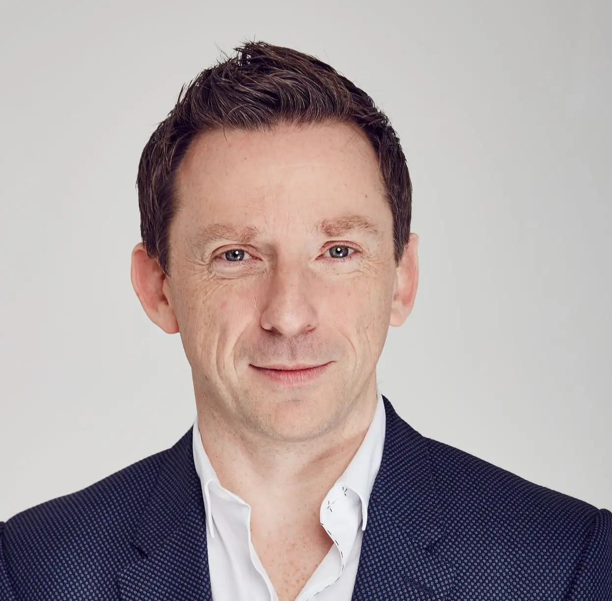 Headshot of man in blue jacket and white shirt