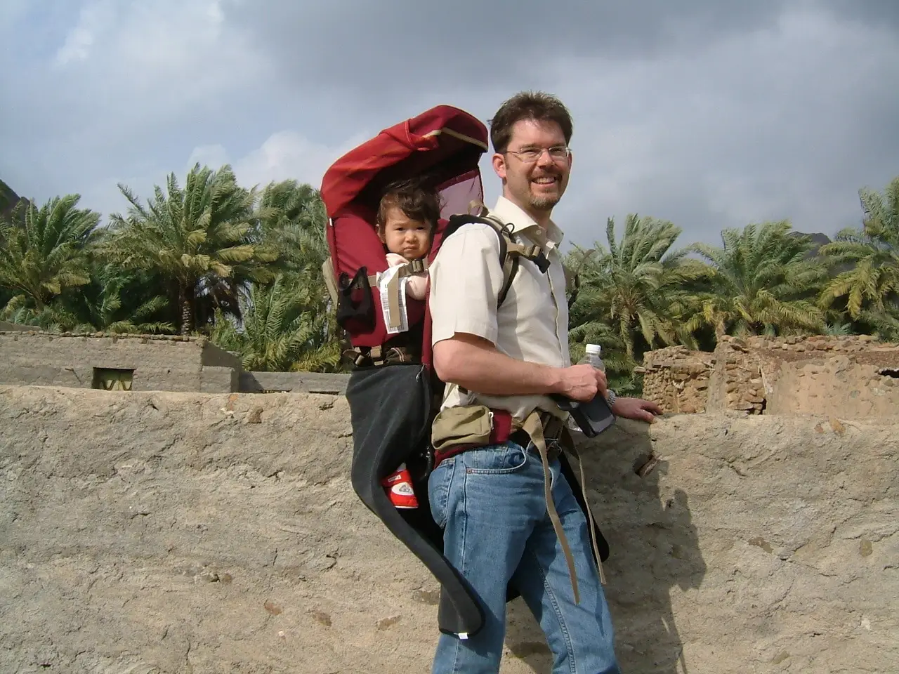 A man holding his child on his back in the Middle East.