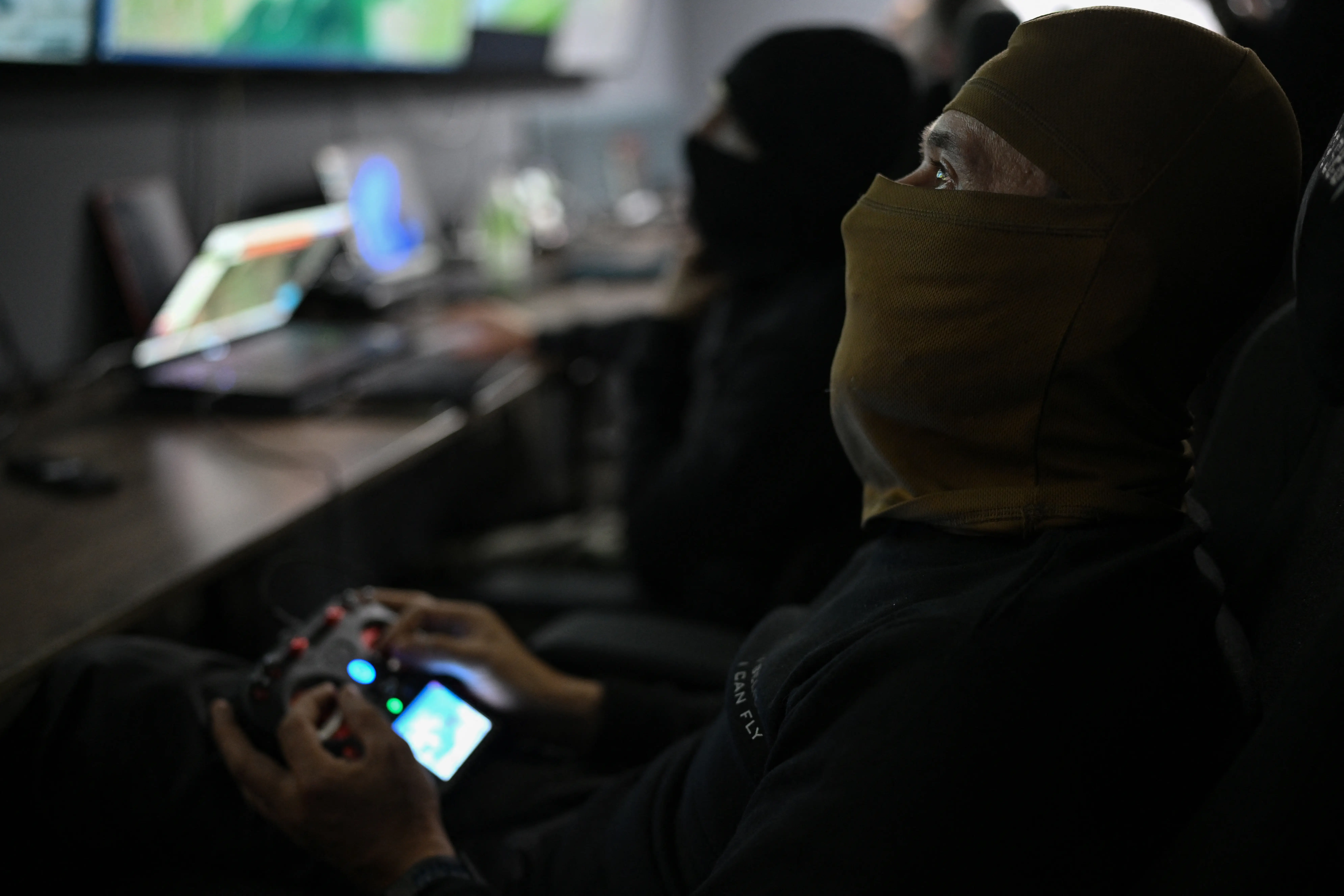 A Ukrainian soldier with a balaclava holds a drone remote control.