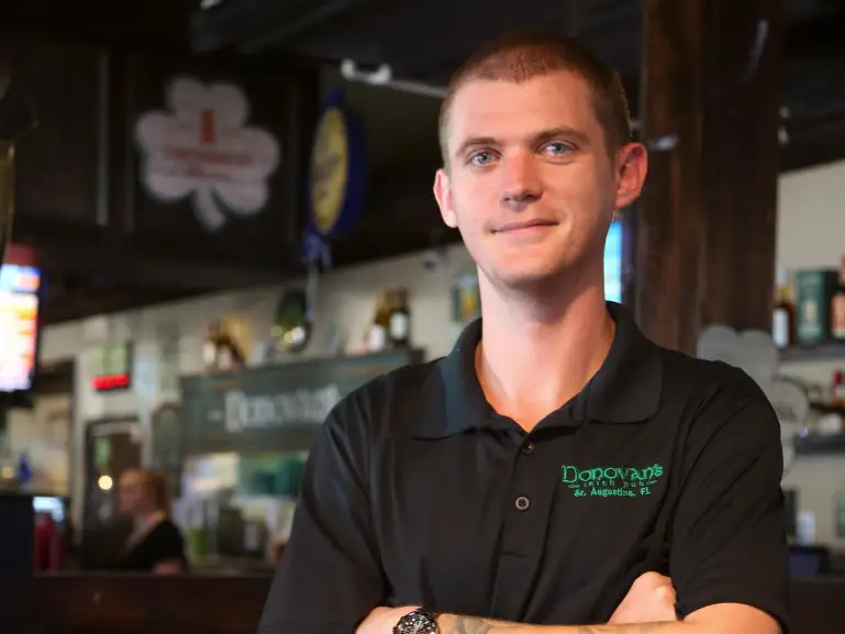 A young man with his arms crossed in a restaurant.