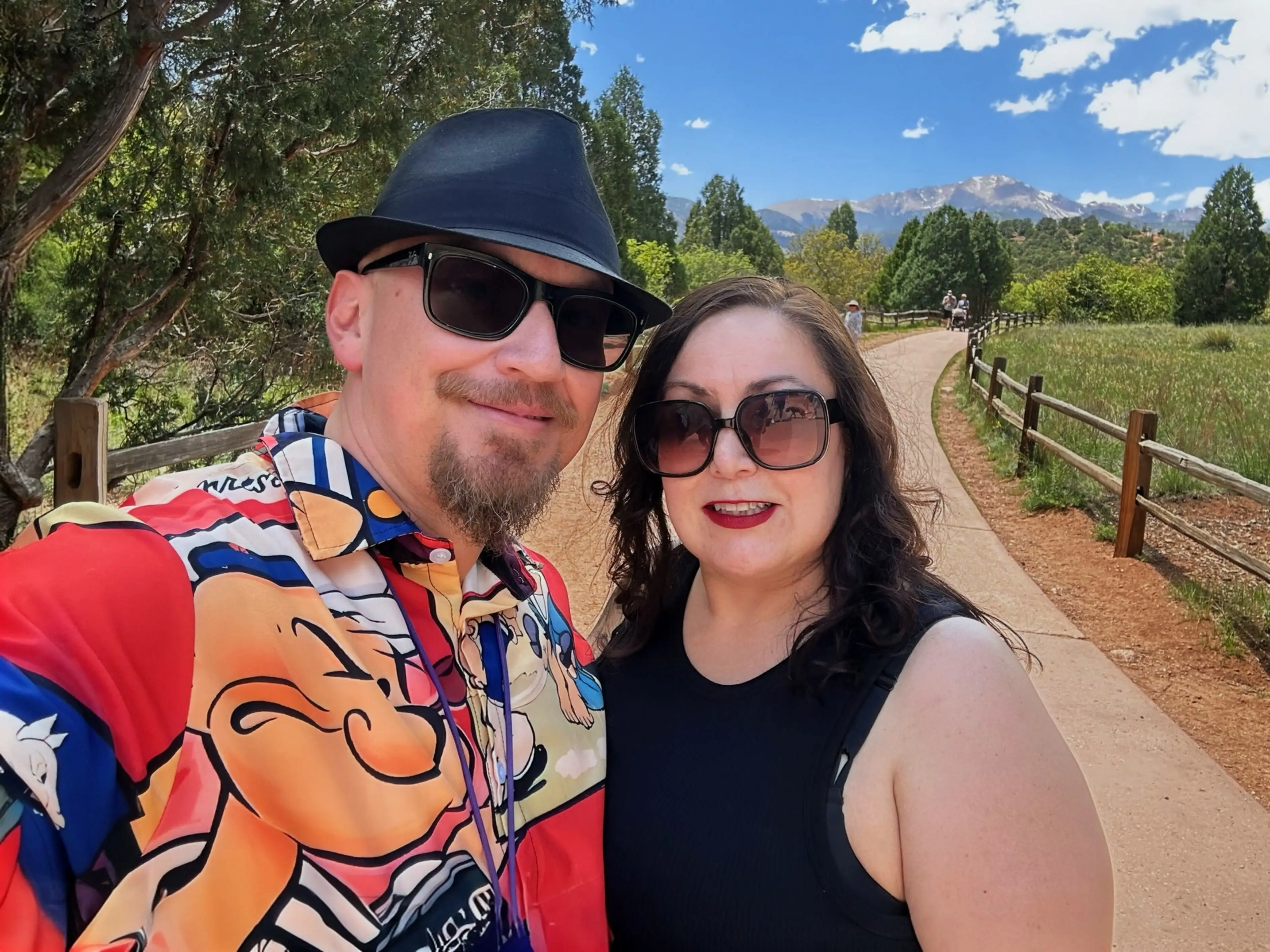 A couple taking a selfie while wearing sunglasses with a mountain range in the background.