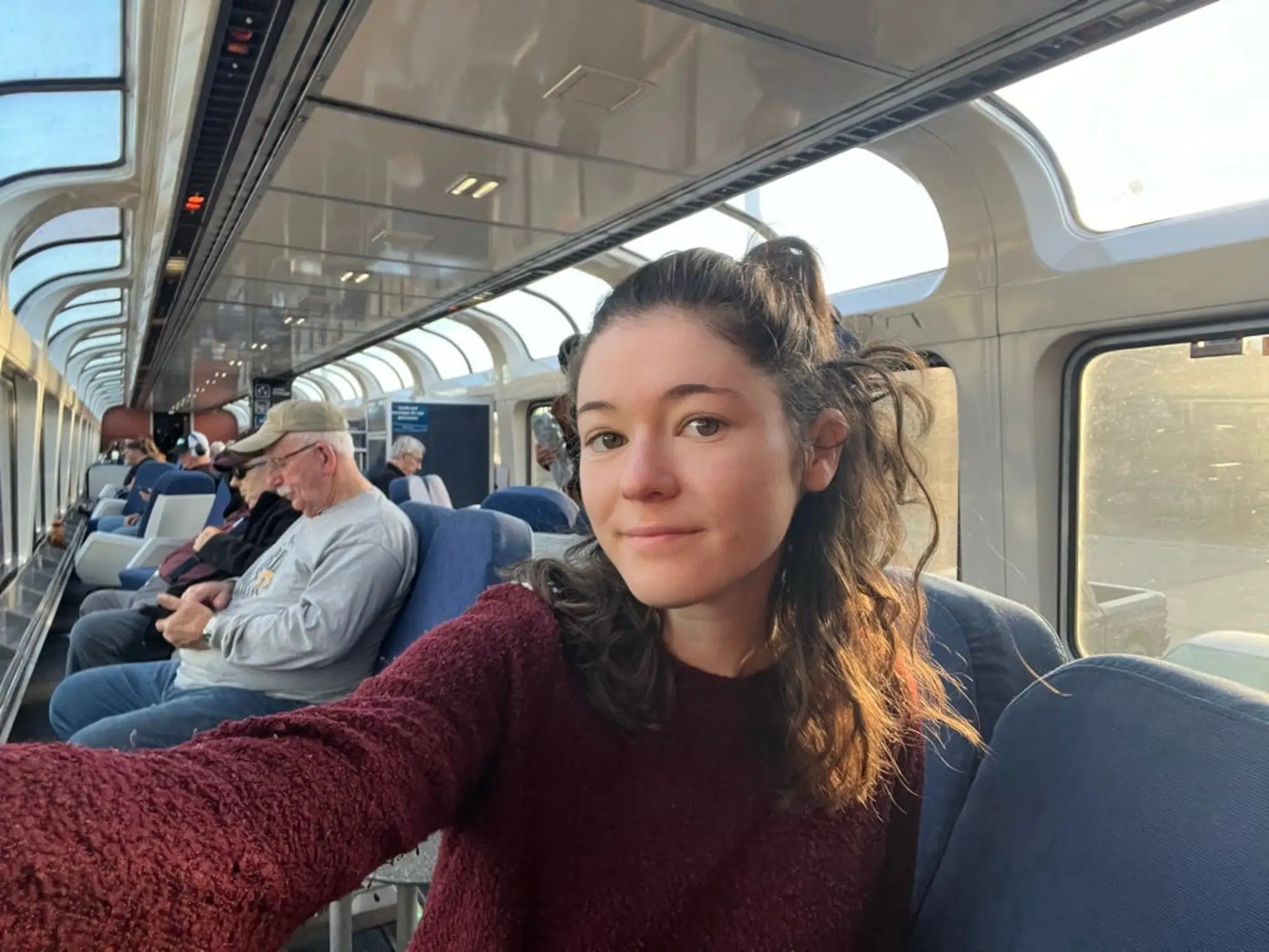 The author taking a selfie in the observation car of an Amtrak train while wearing a red sweater.