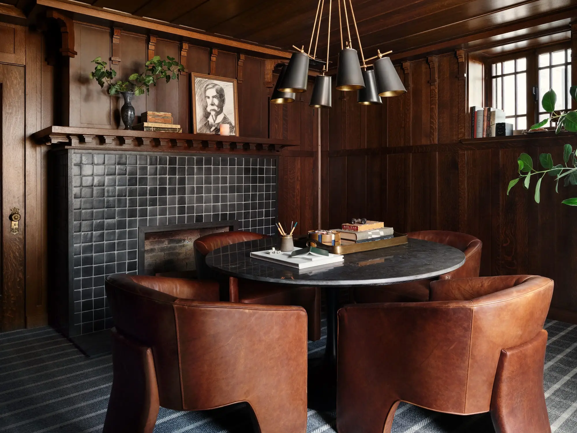 A dining room with a tile fireplace and modern, round table.