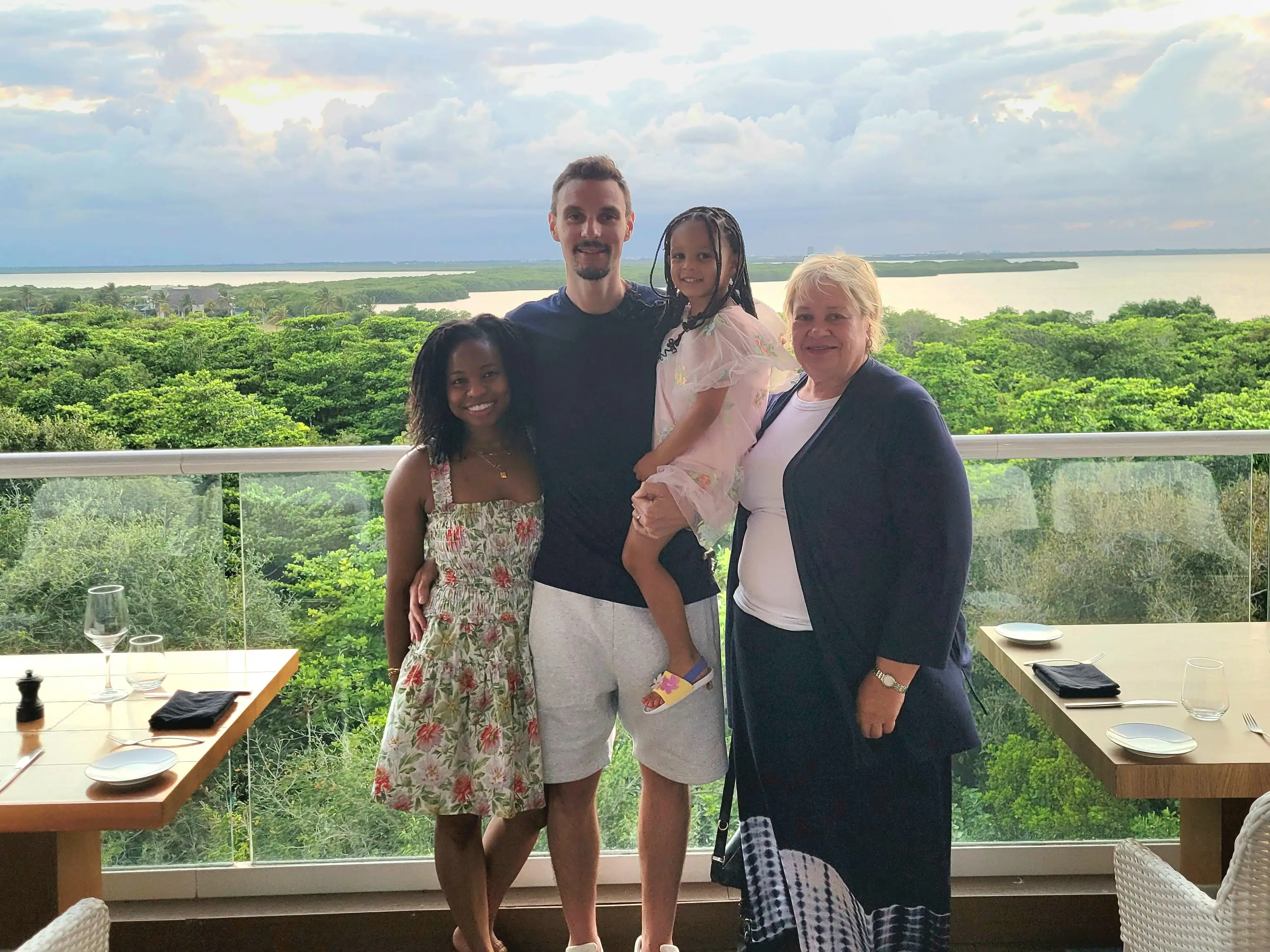 Cher, her husband, young daughter, and mother-in-law pose at a scenic point on a resort.