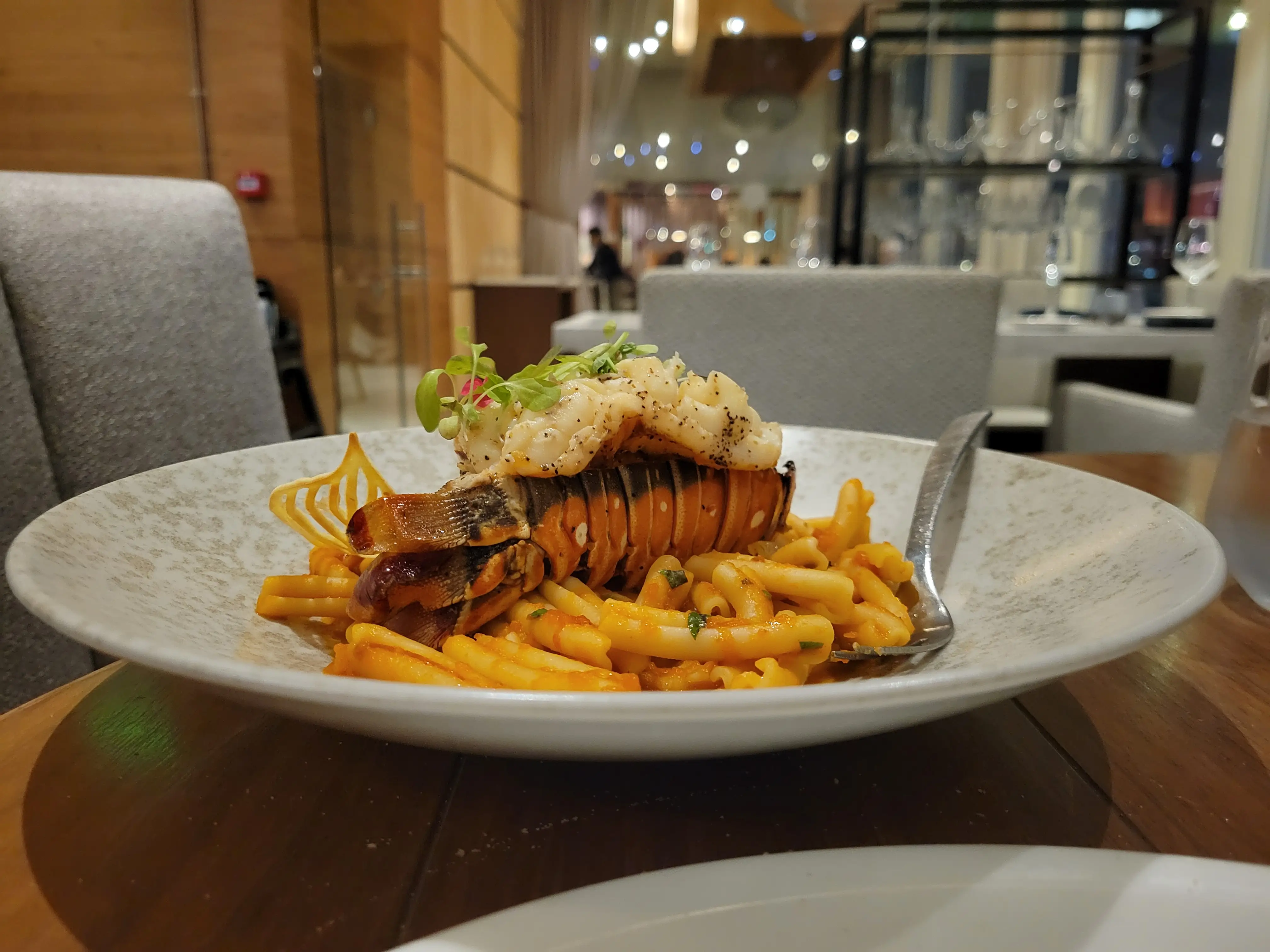 A plate of pasta topped with a lobster tail.