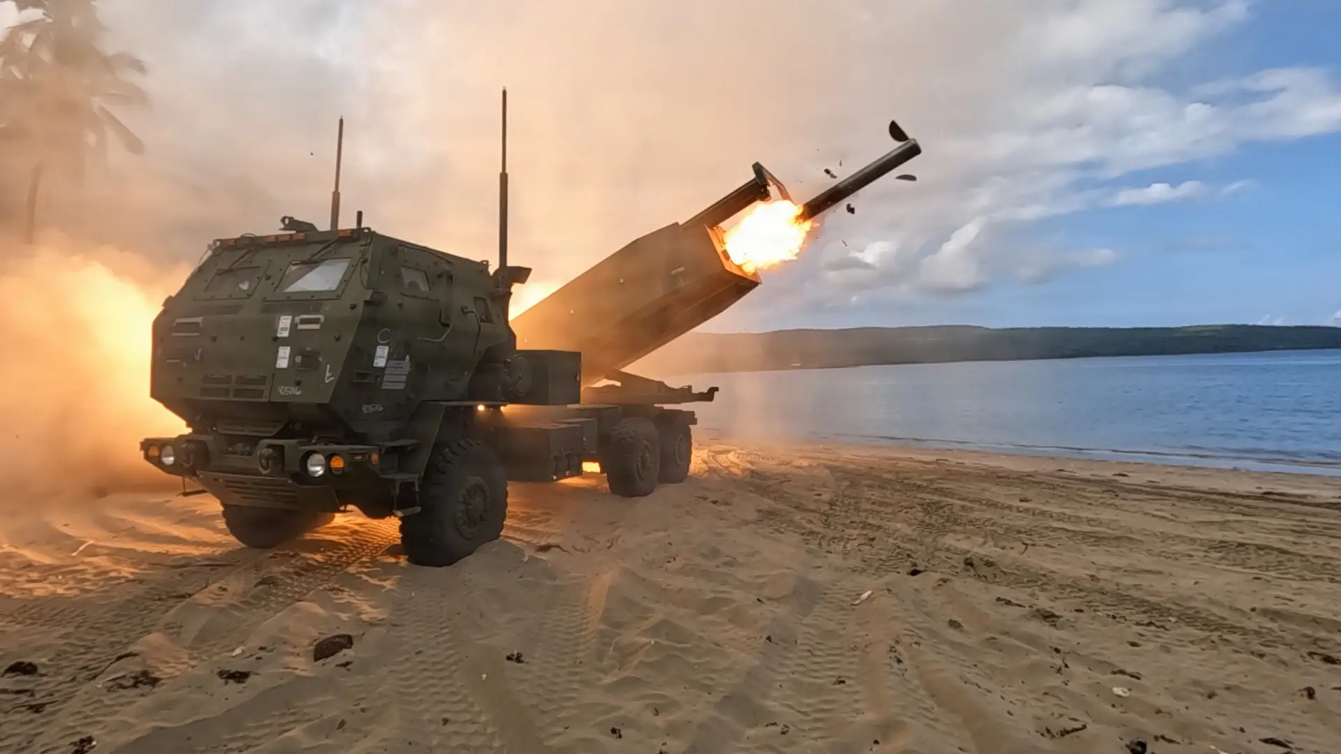 A US Army M142 High Mobility Artillery Rocket System fires on a beach.
